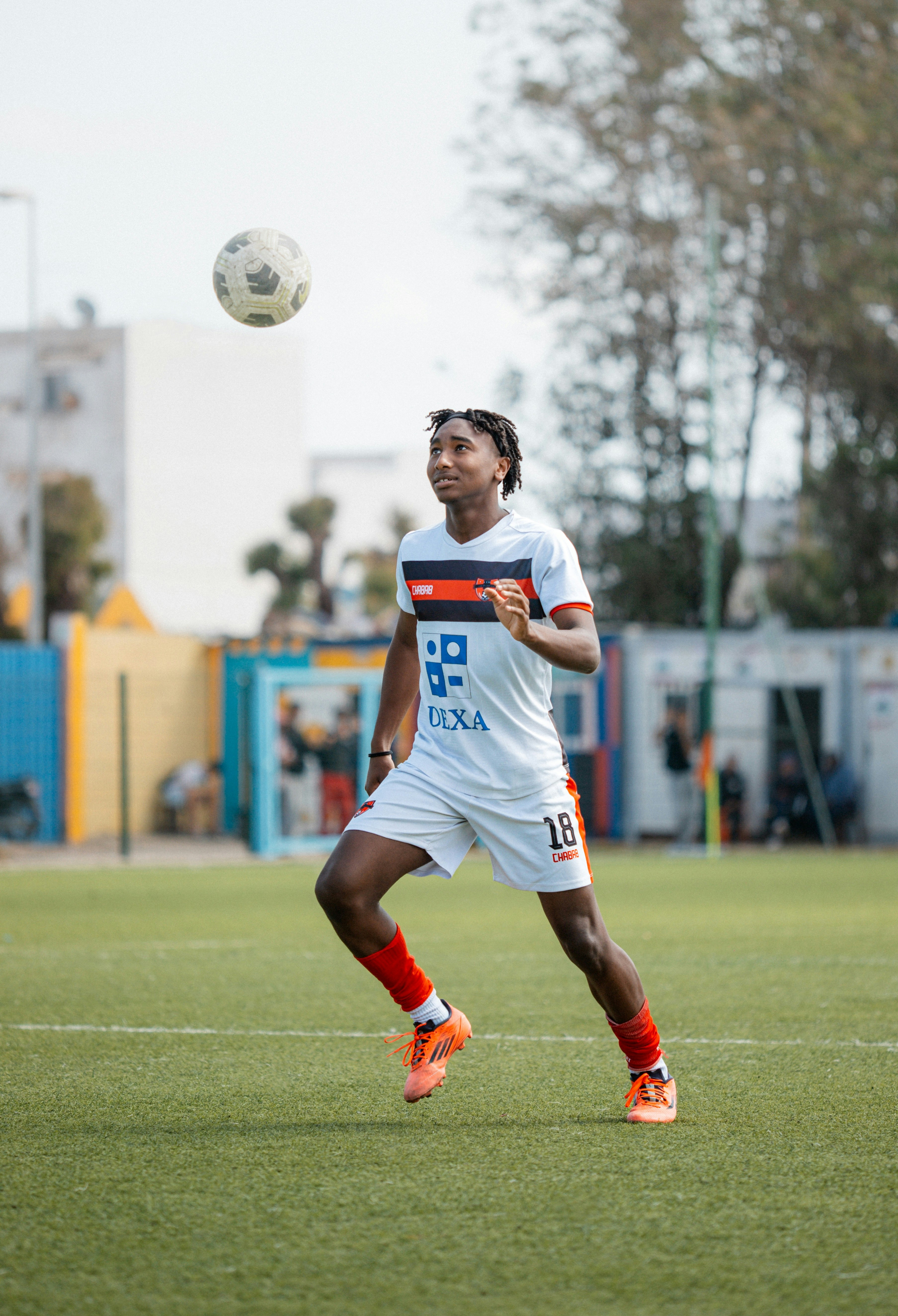 Pemain sepak bola menyundul bola di lapangan.