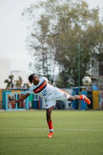 A soccer player kicks the ball mid-air.