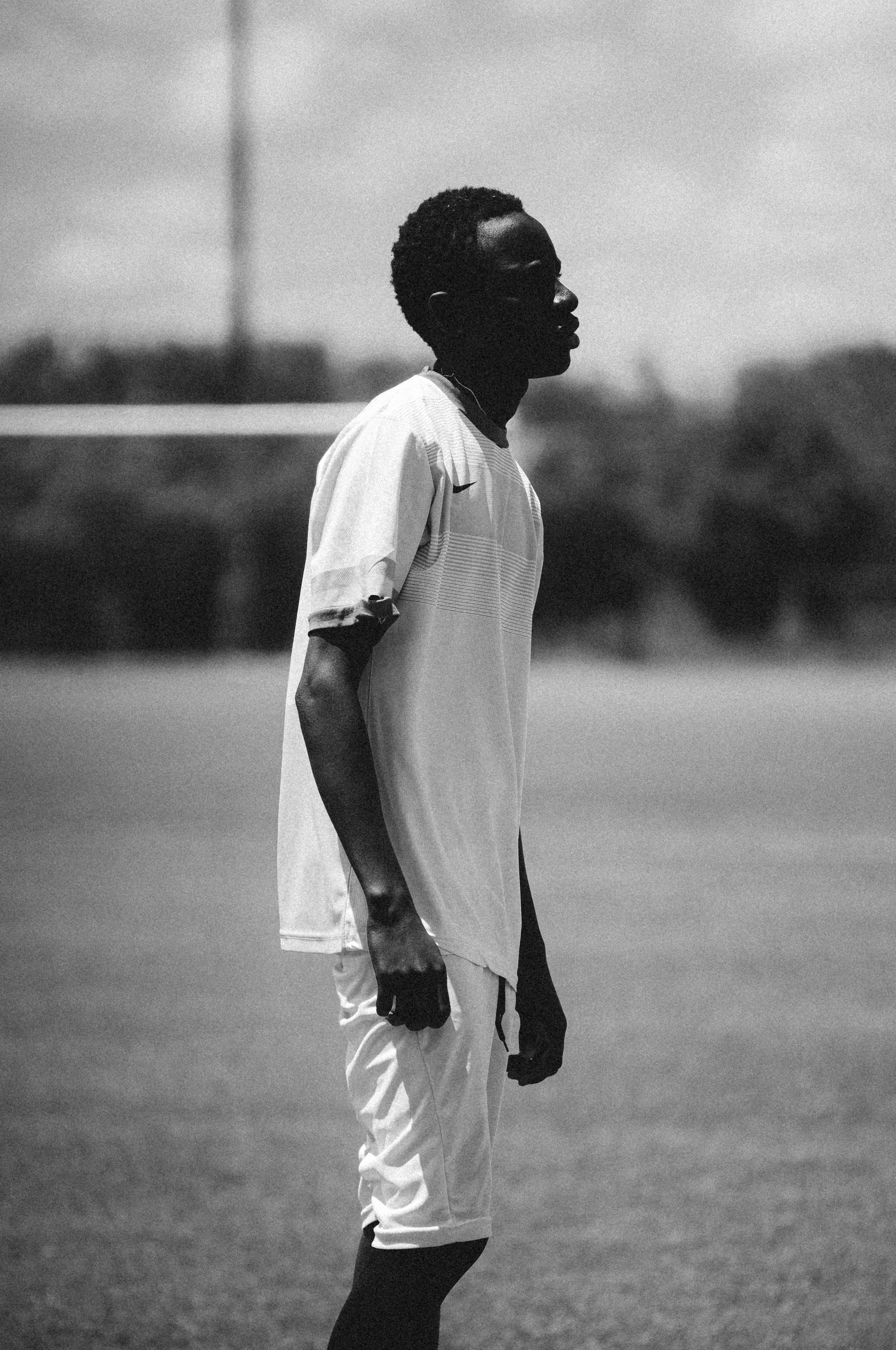 A young man stands on a grass field.