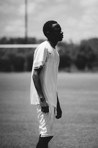 A young man stands on a grass field.