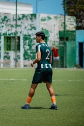A soccer player stands on the field, focused.