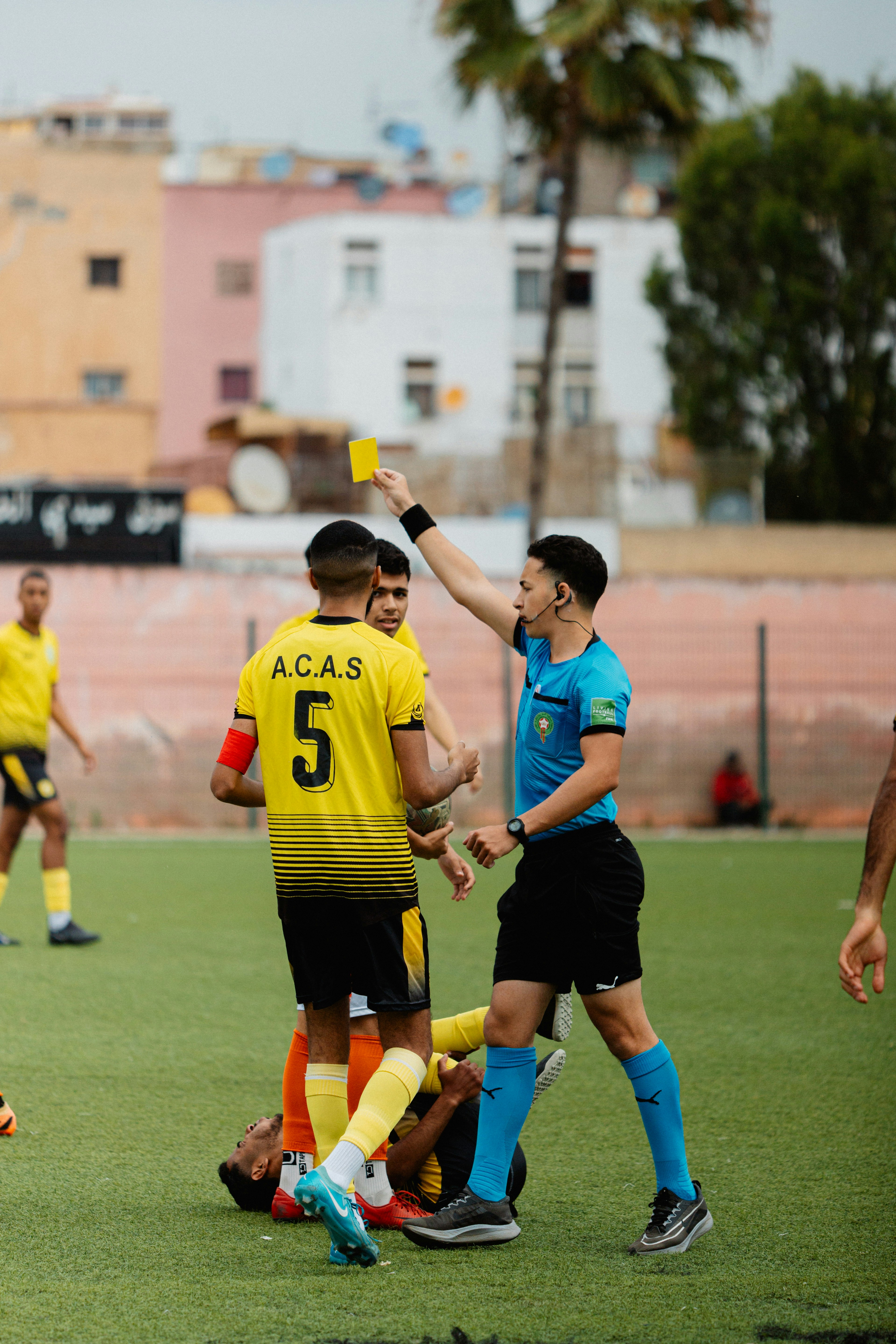 Wasit menunjukkan kartu kuning selama pertandingan sepak bola.