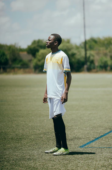 A soccer player stands on a field looking ahead.