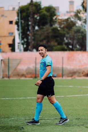 A soccer referee walks on a green field.
