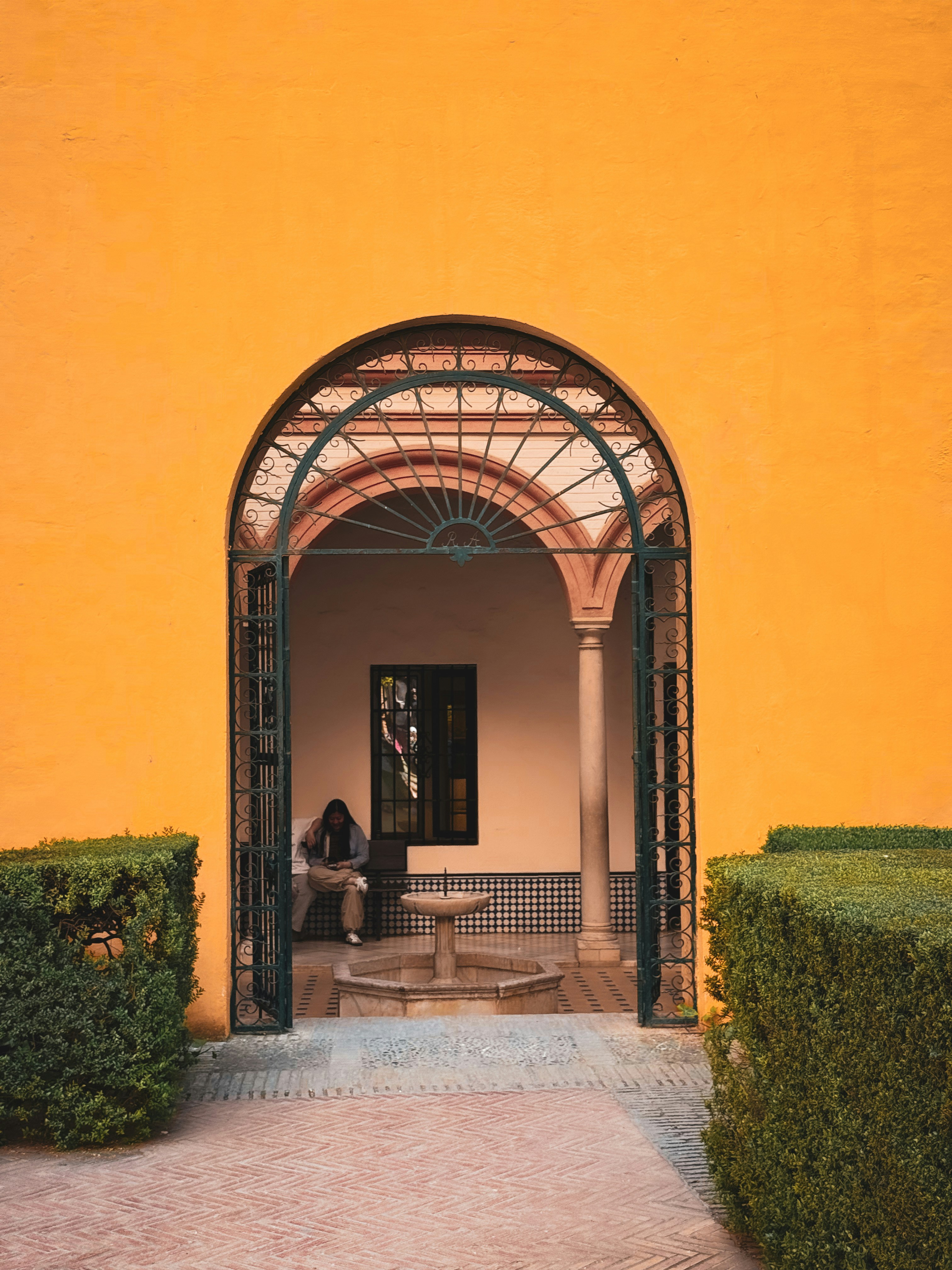 A person sits inside an arched entryway.
