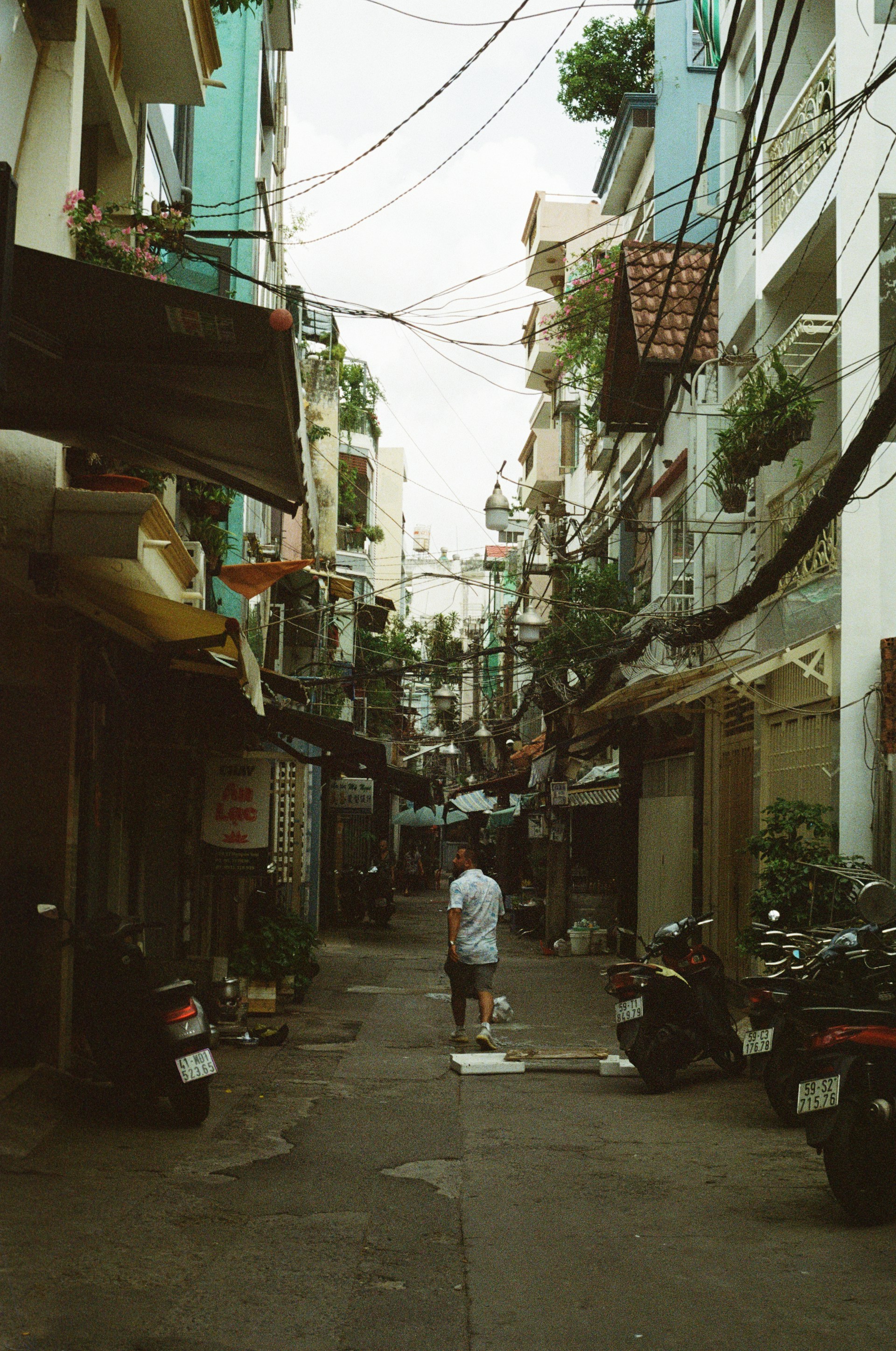 A man walks down a narrow street in the city.