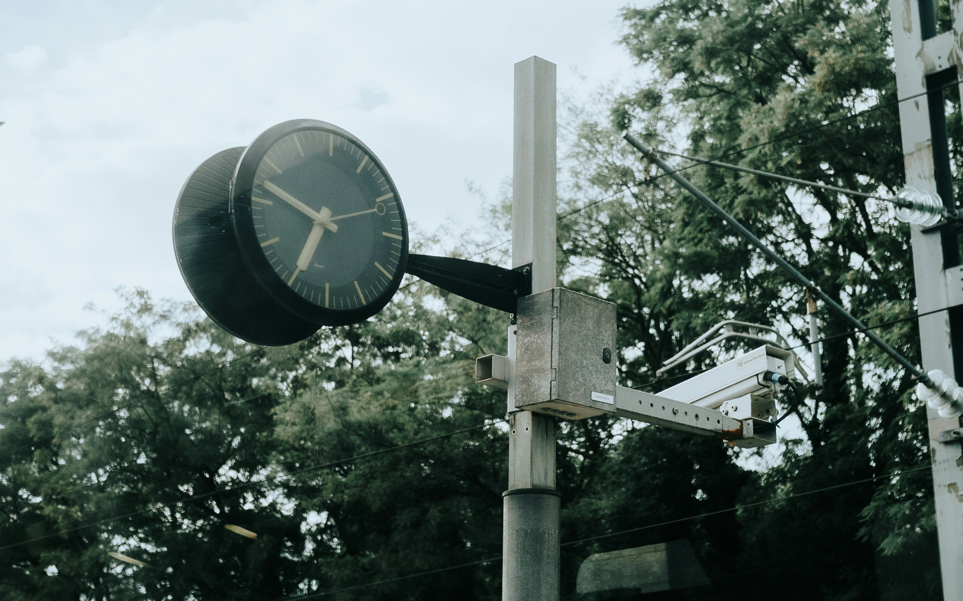 A double-sided clock is displayed outdoors.