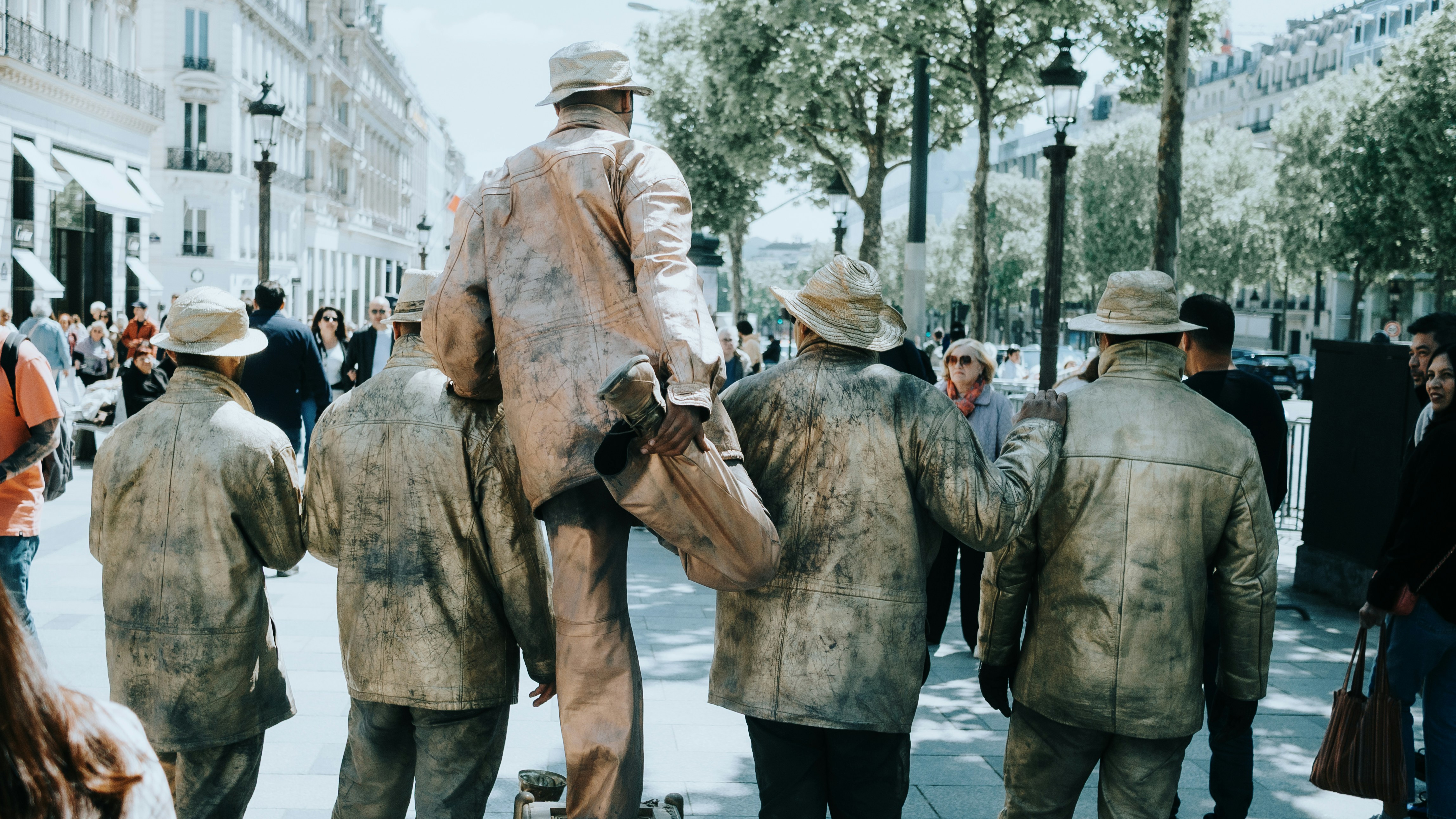 Street performers posing as statues on a city street.