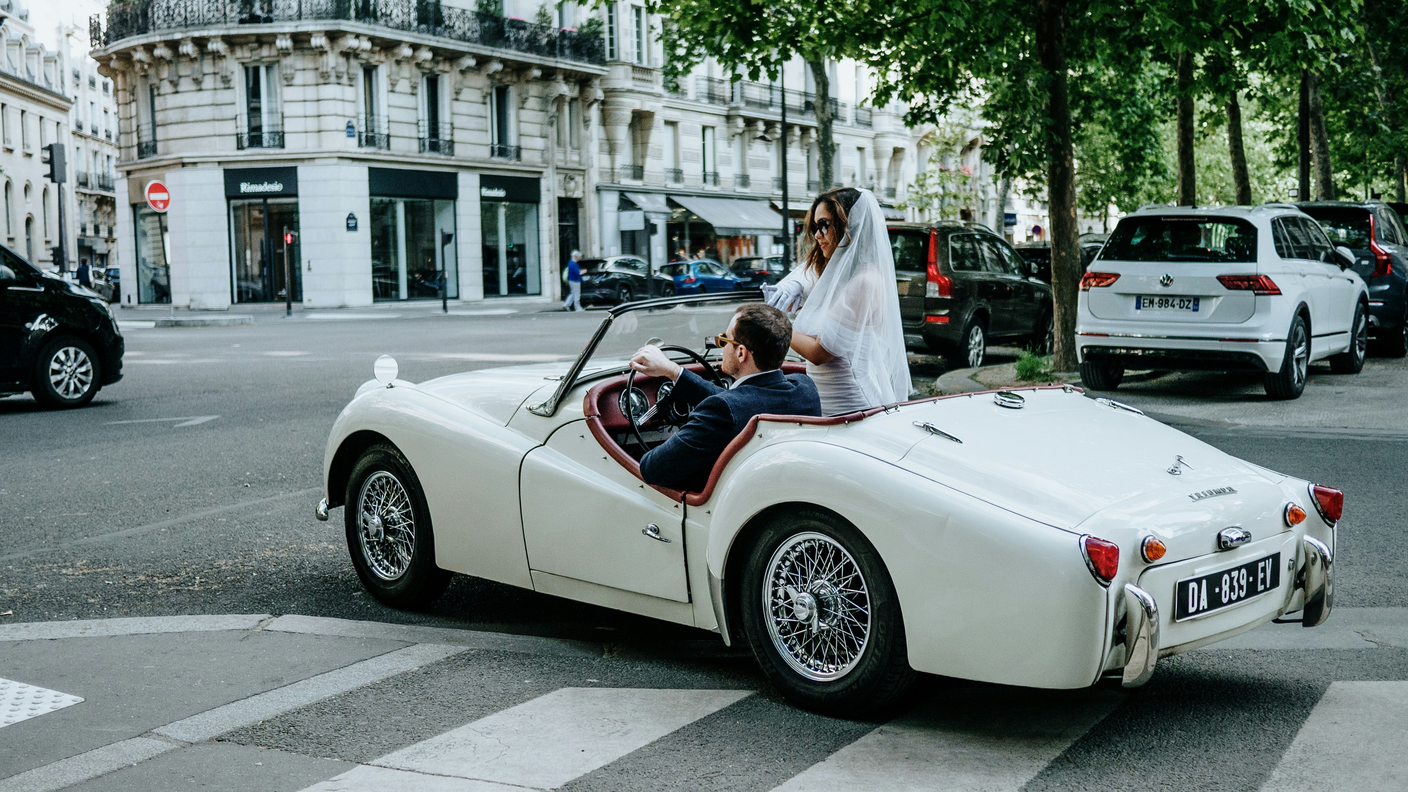 La novia y el novio se van en un coche antiguo.