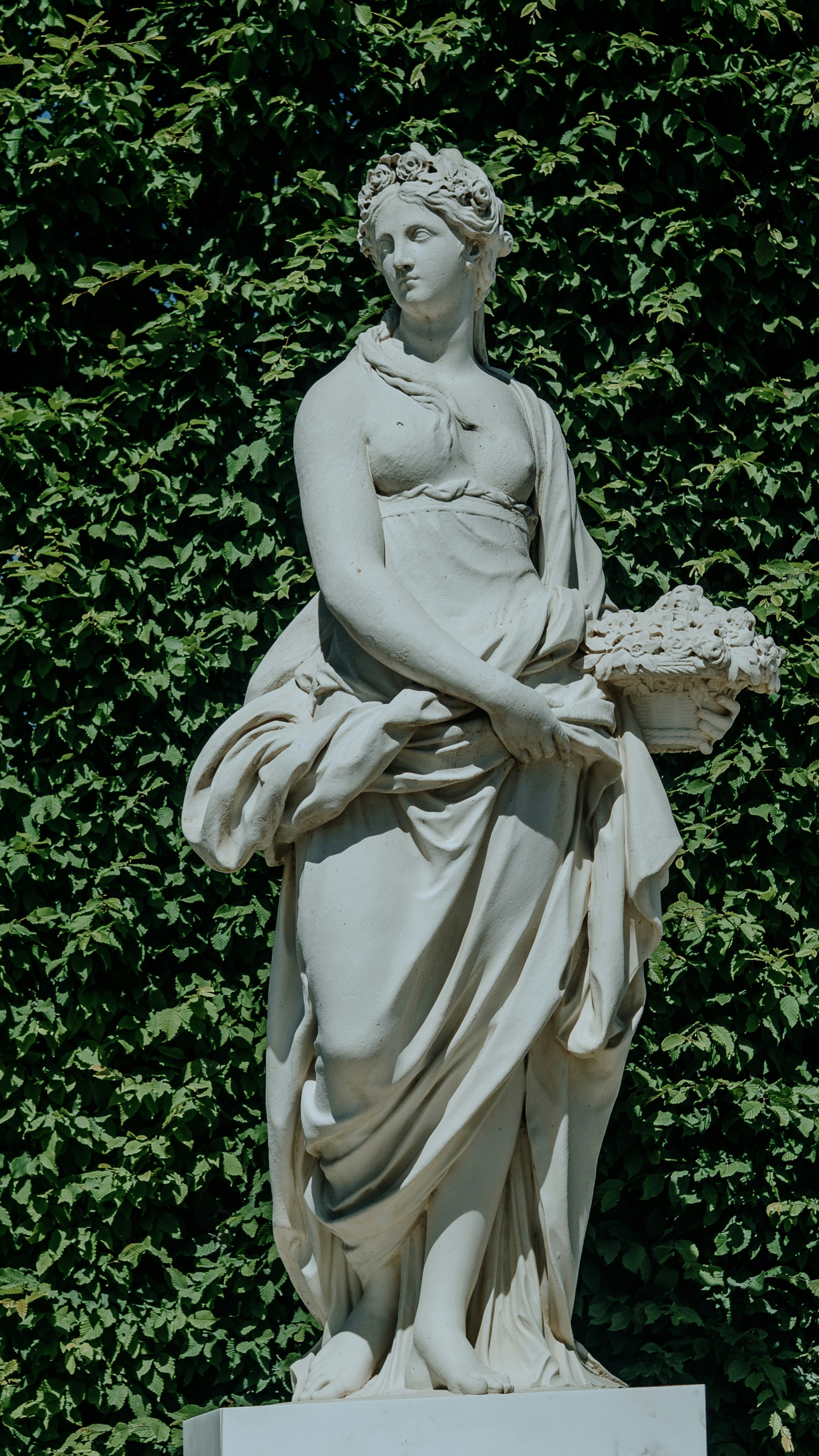 Estatua de una mujer sosteniendo una cesta de flores.