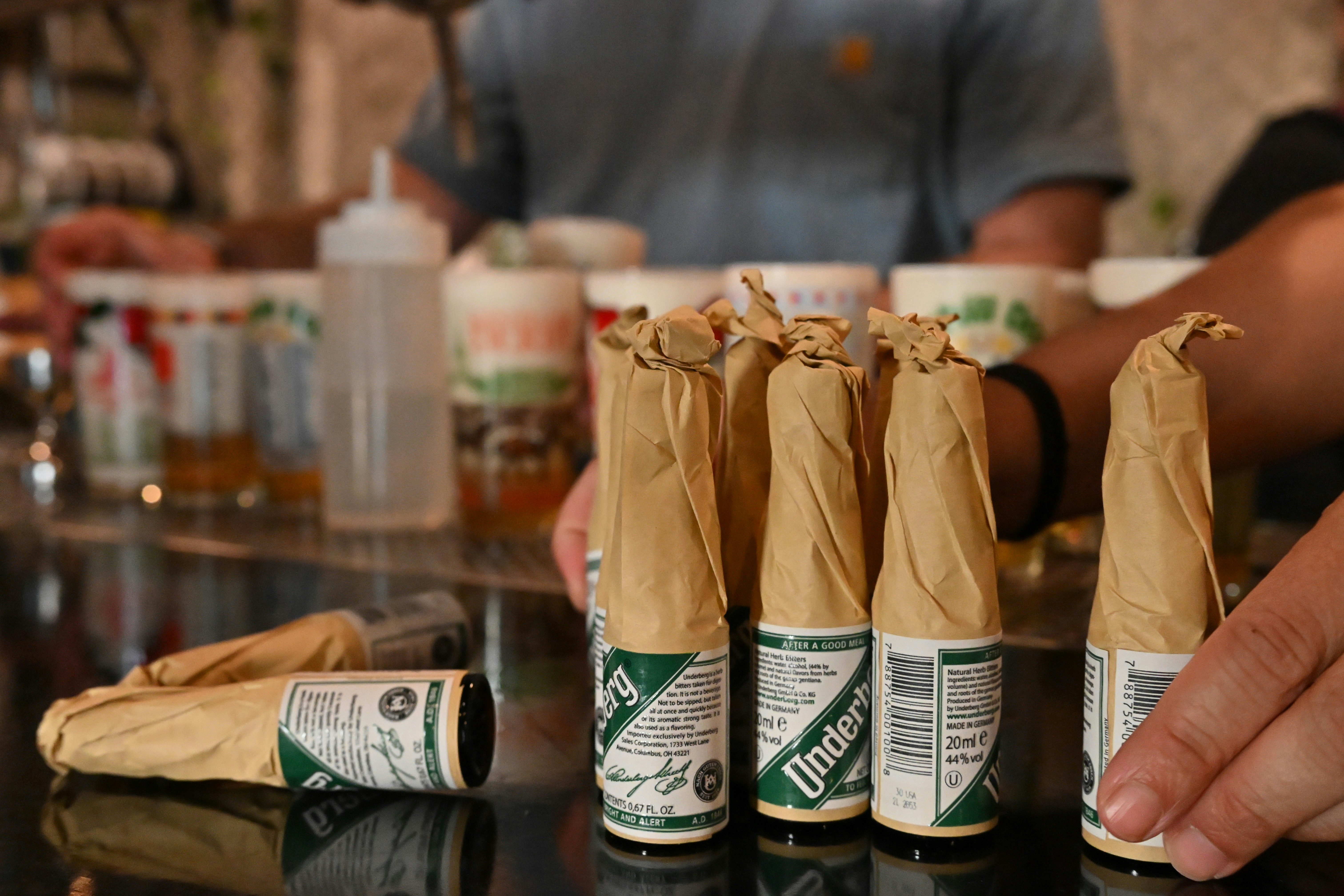 Bottles wrapped in brown paper sit on a bar.