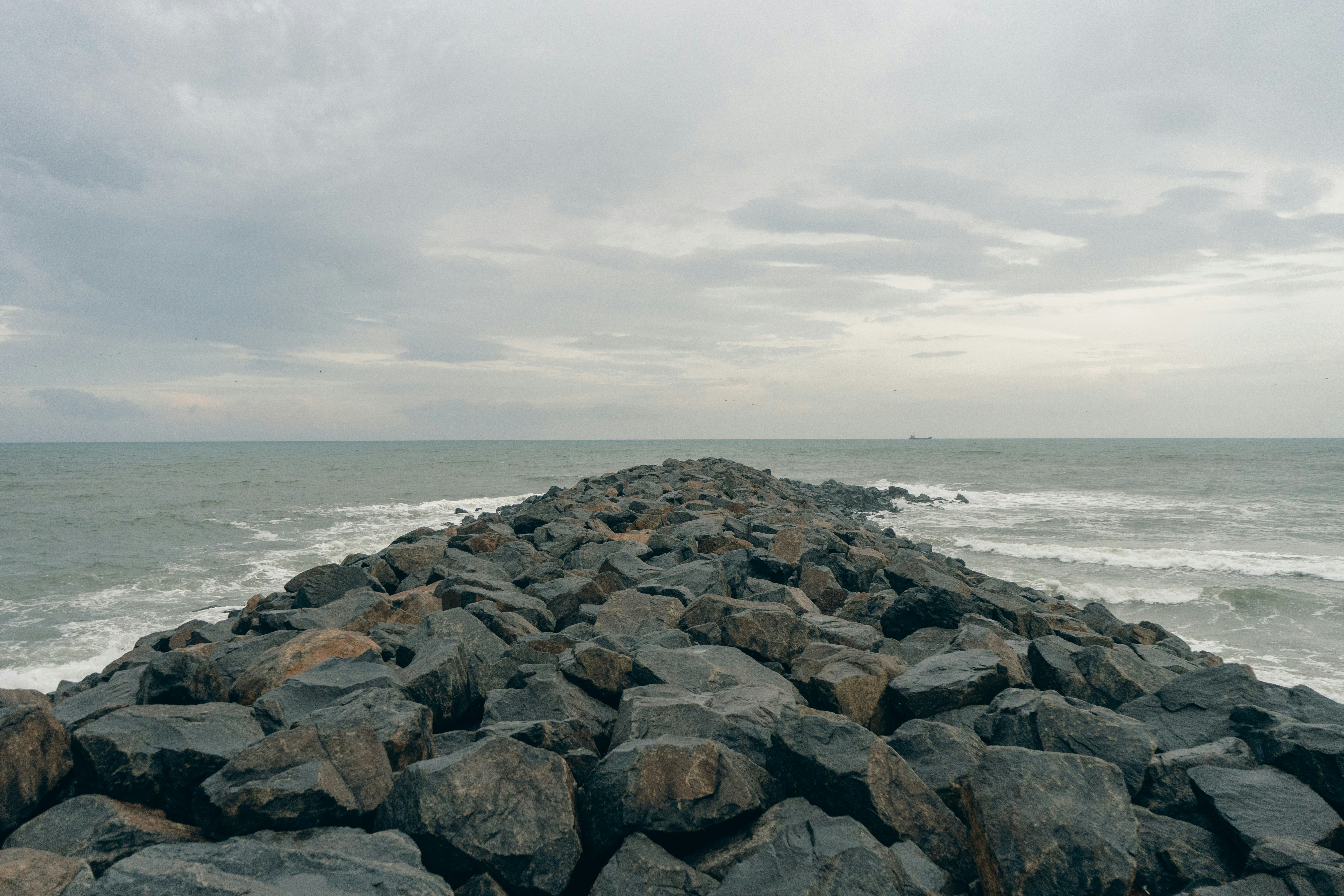 A rocky jetty extends into the stormy sea.