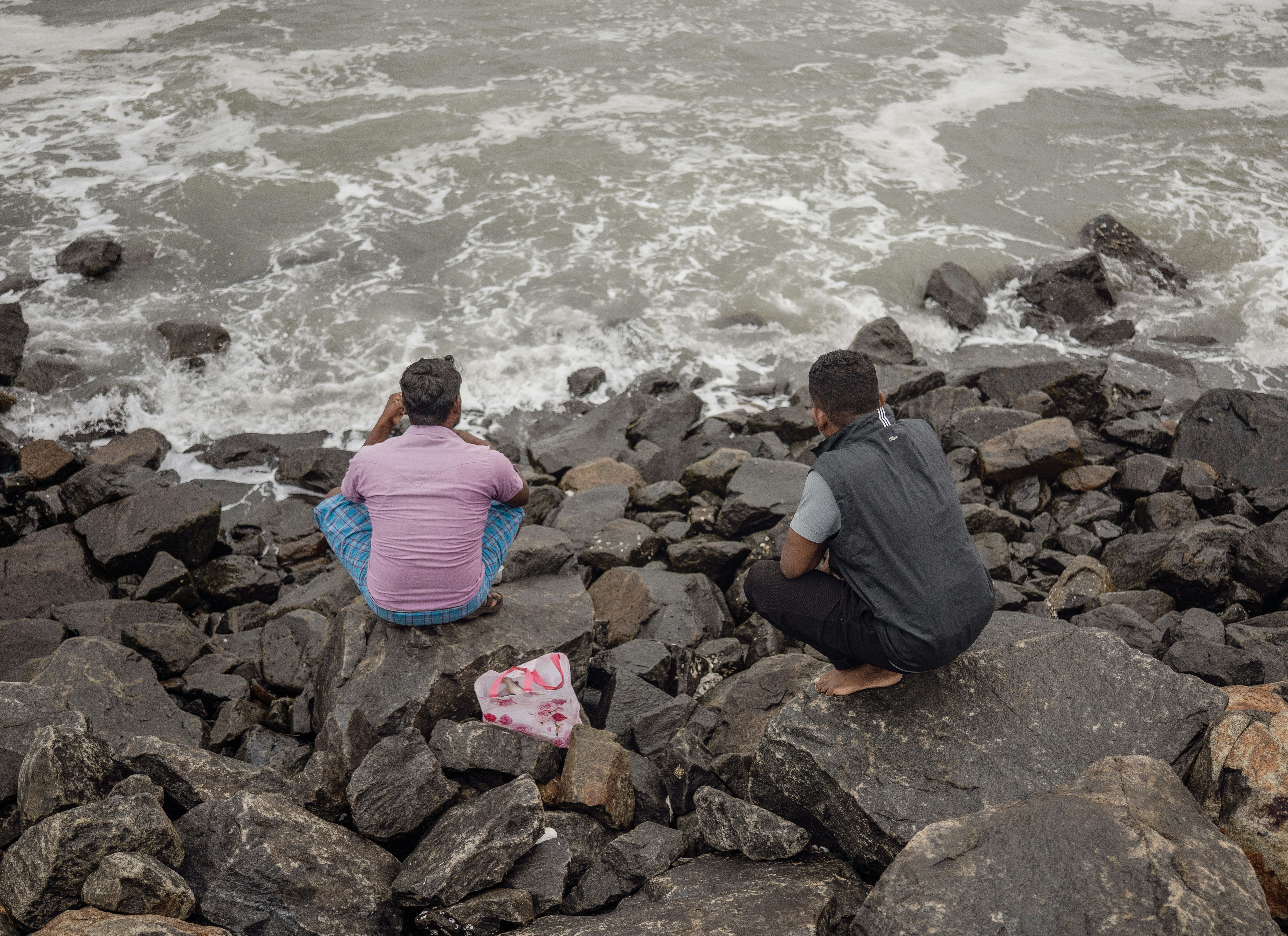 Two people sit and observe the ocean.