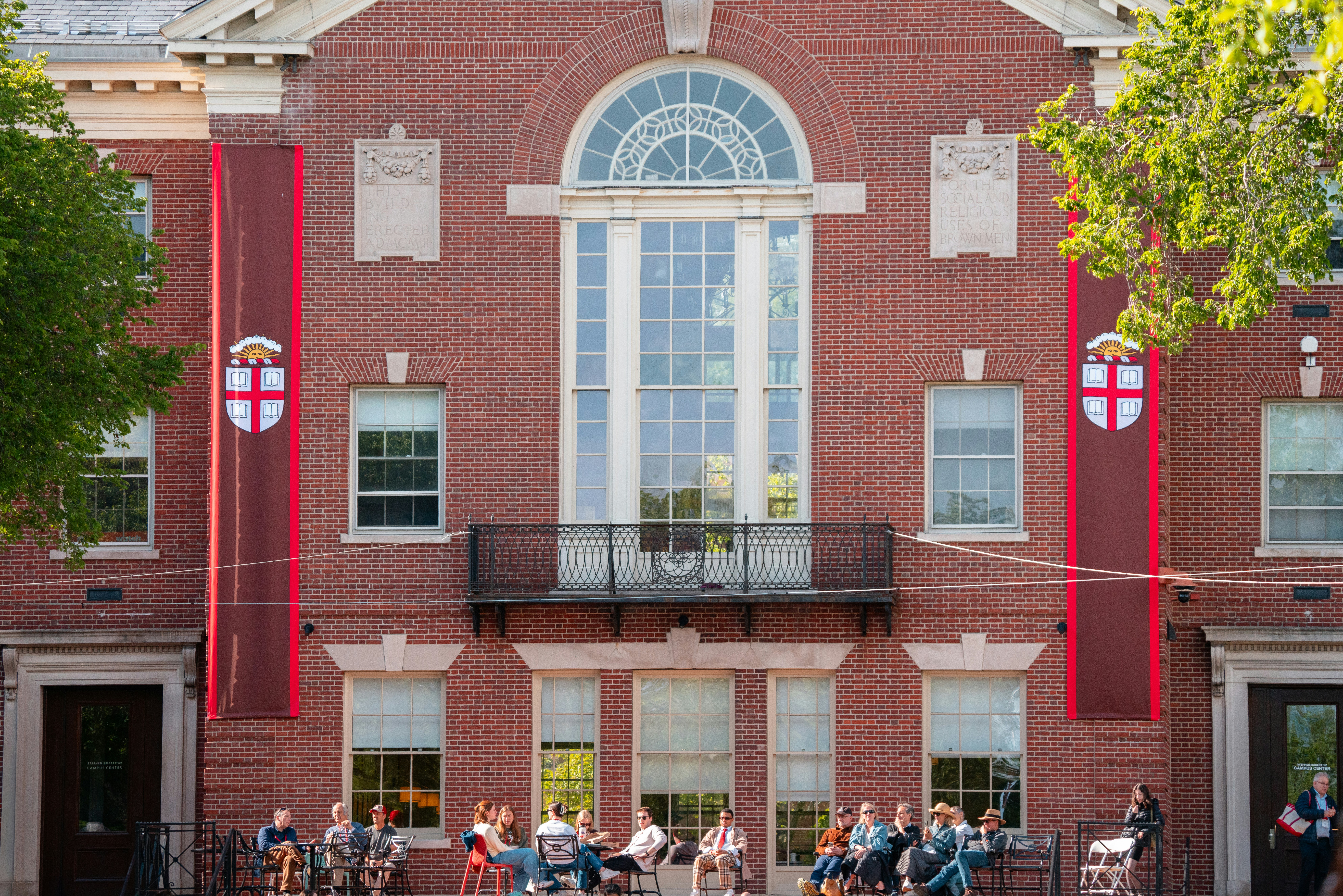 A group of people sits in front of a building.