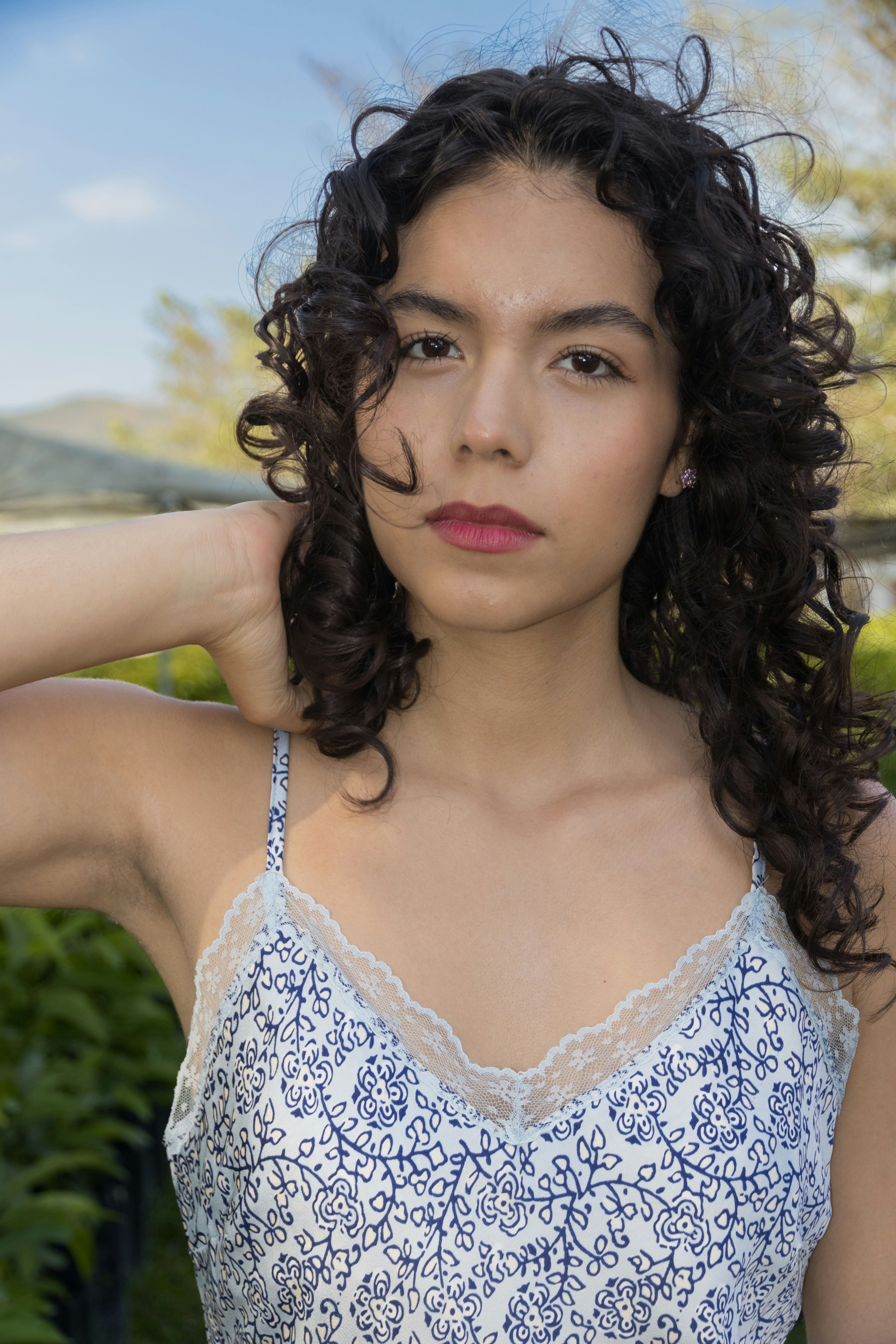 A young woman poses outdoors, looking at the viewer