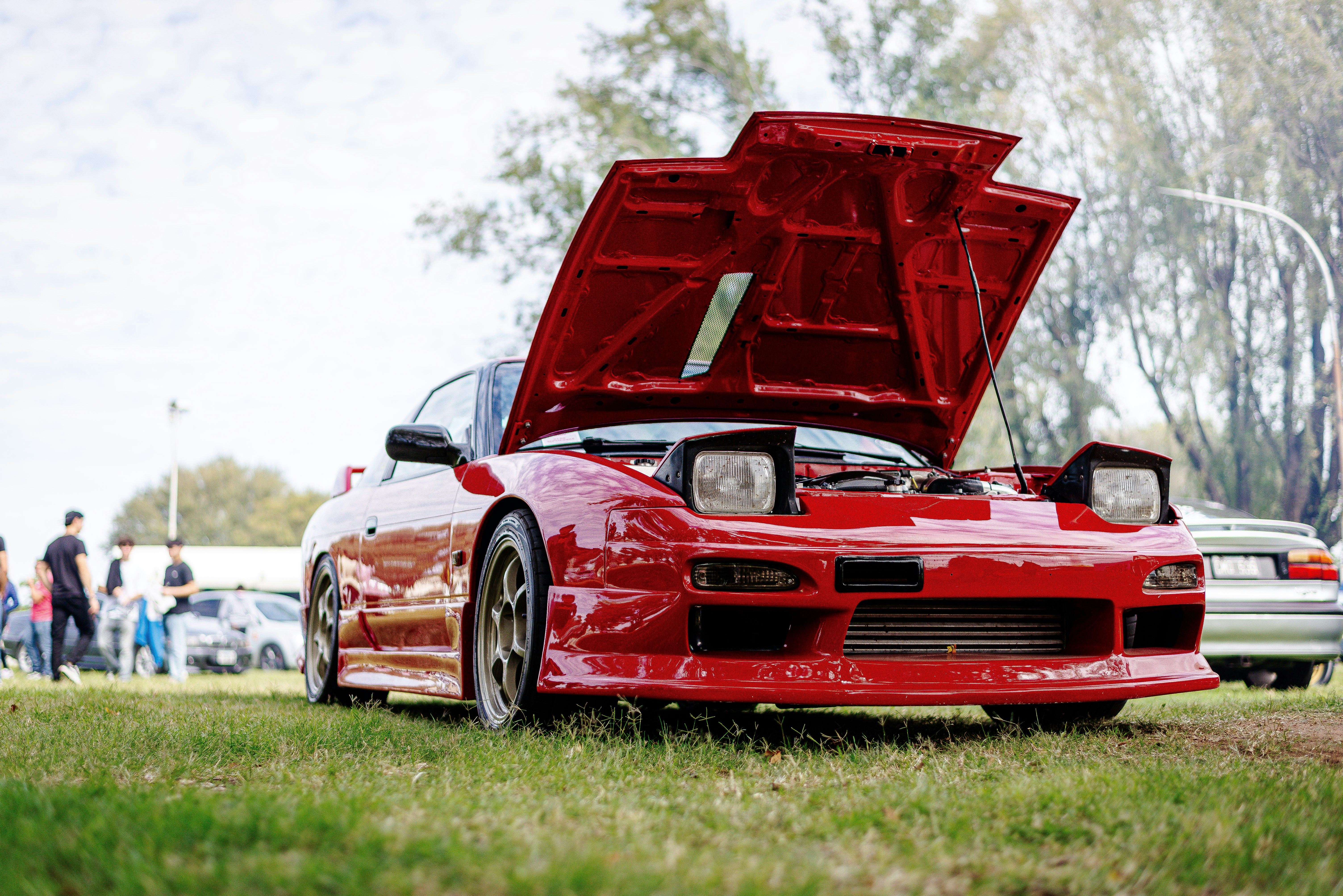 Red sports car with its hood open.