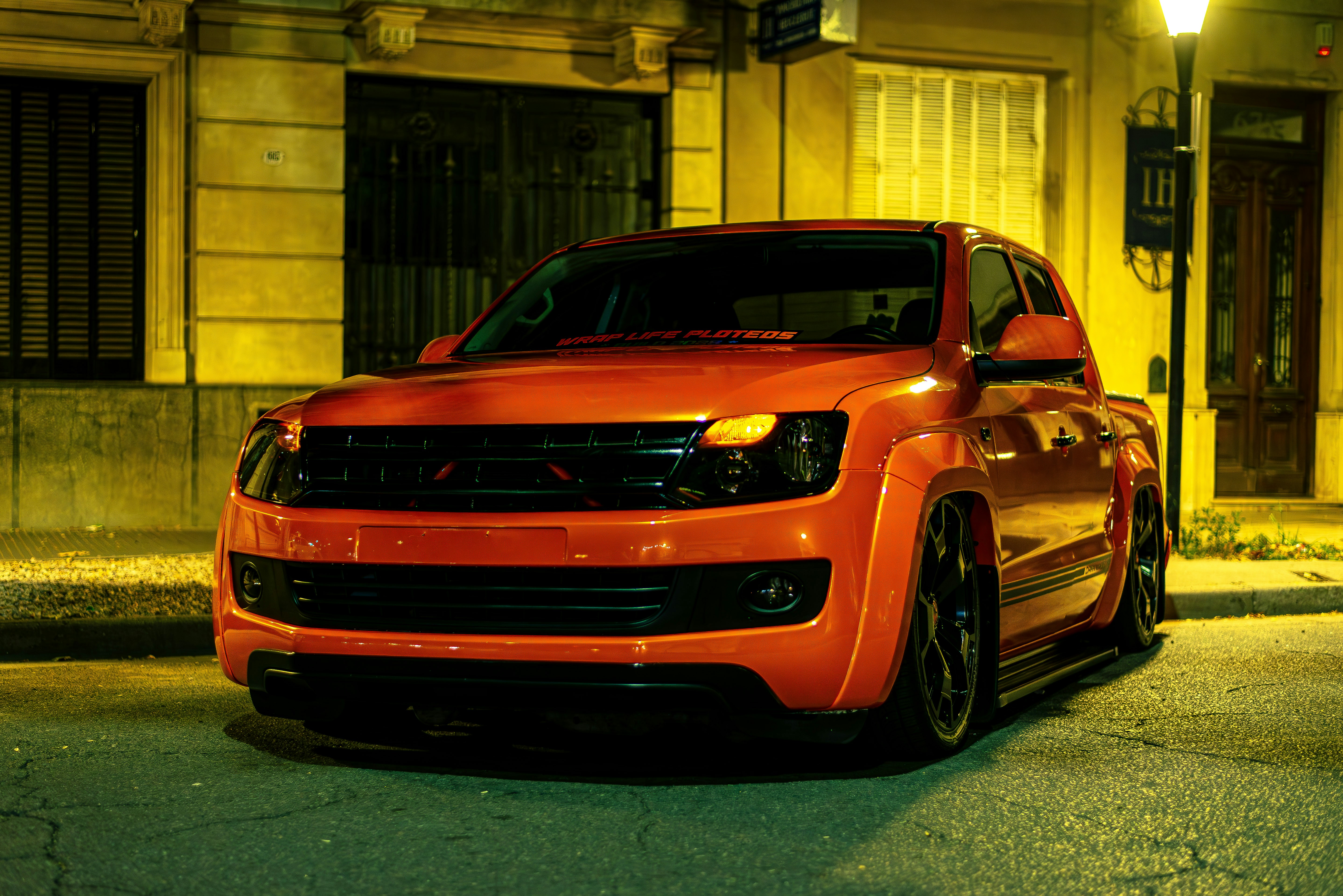 A red truck is parked on the street at night.