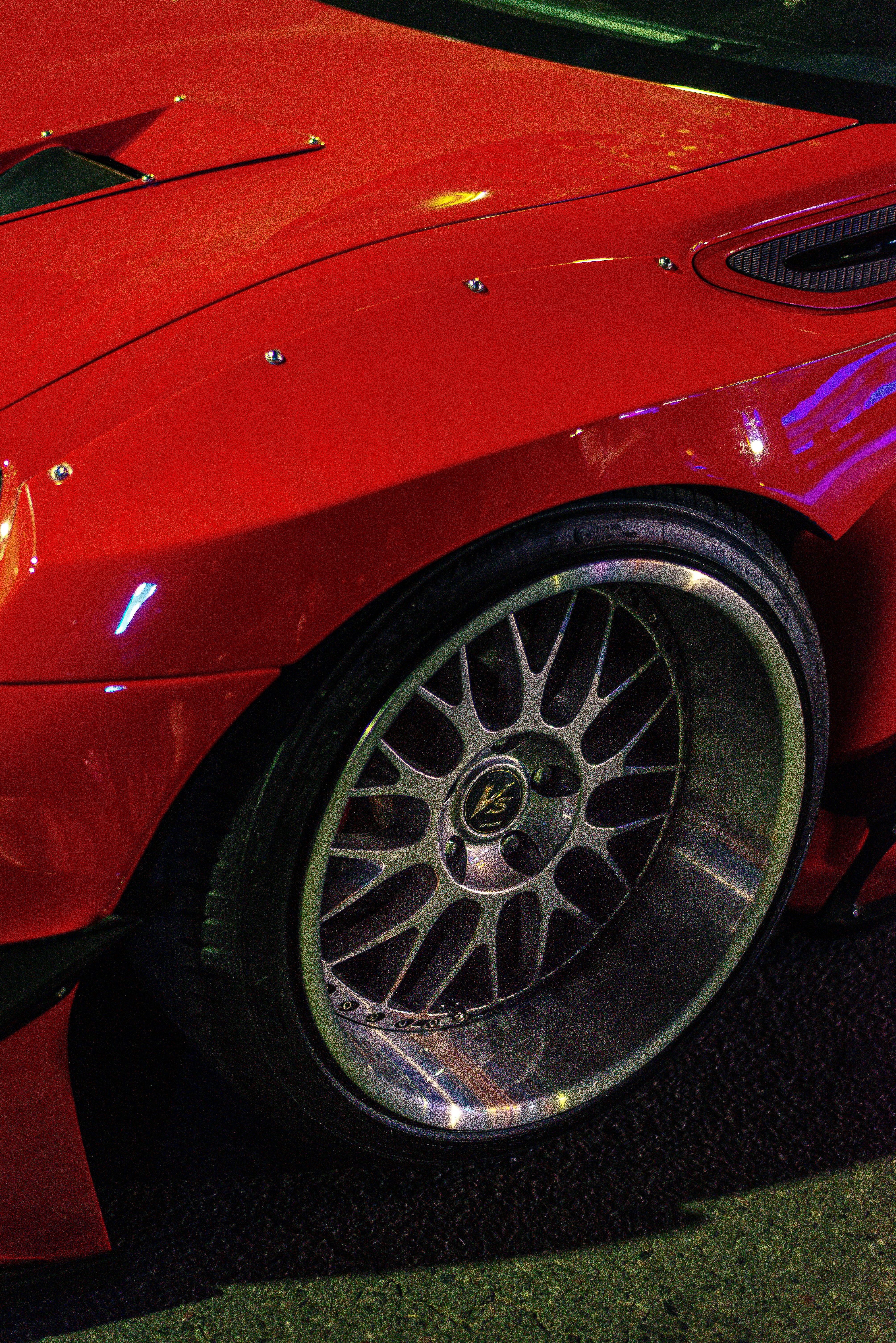 A red car's wheel and fender are shown.