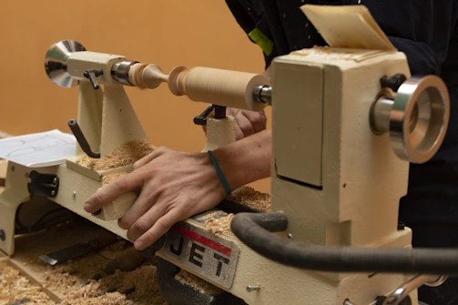 A woodworker uses a lathe to shape wood.