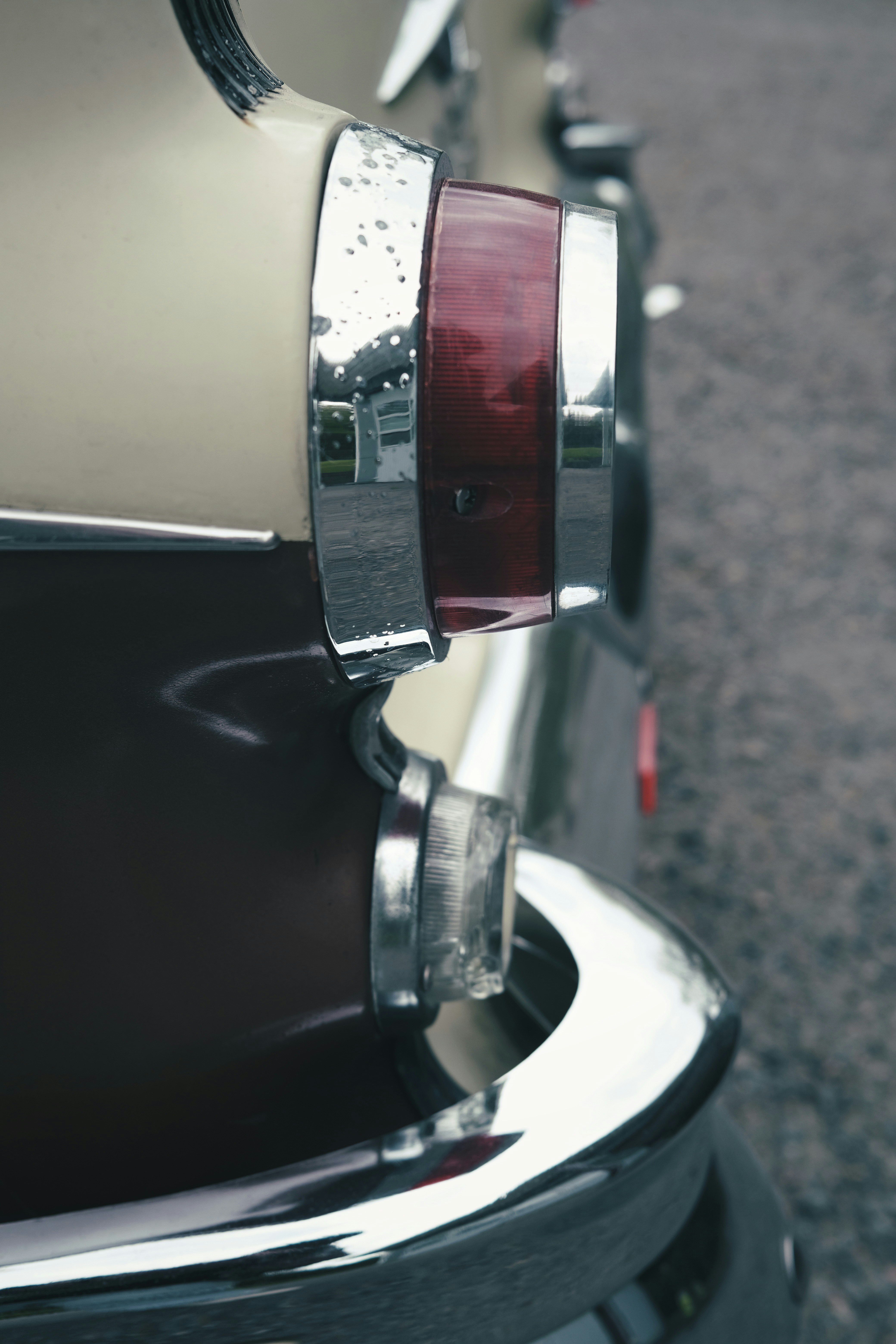 A left tail light and chrome bumper of a 1955 Pontiac Chieftain.