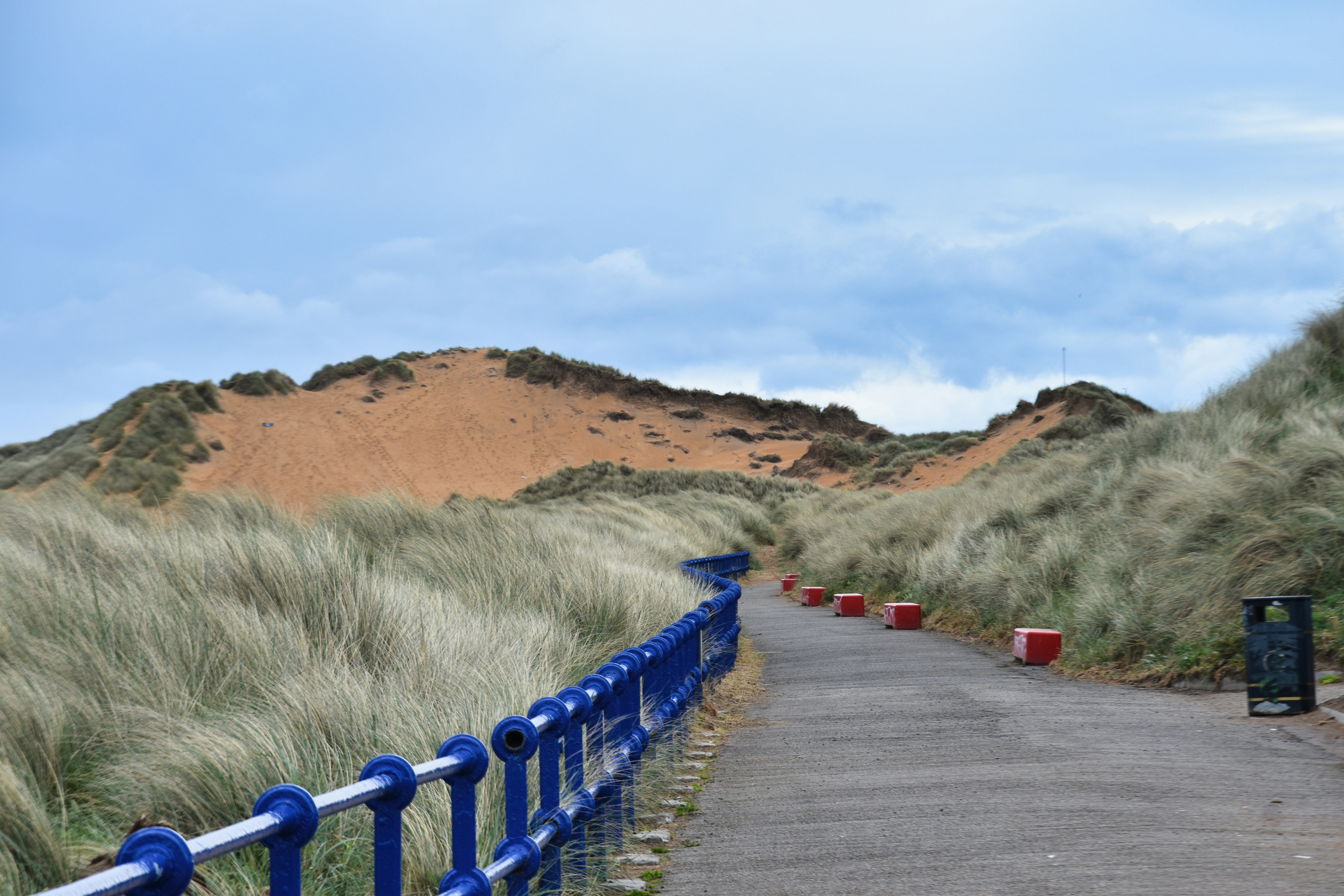 A path leads through grassy dunes.