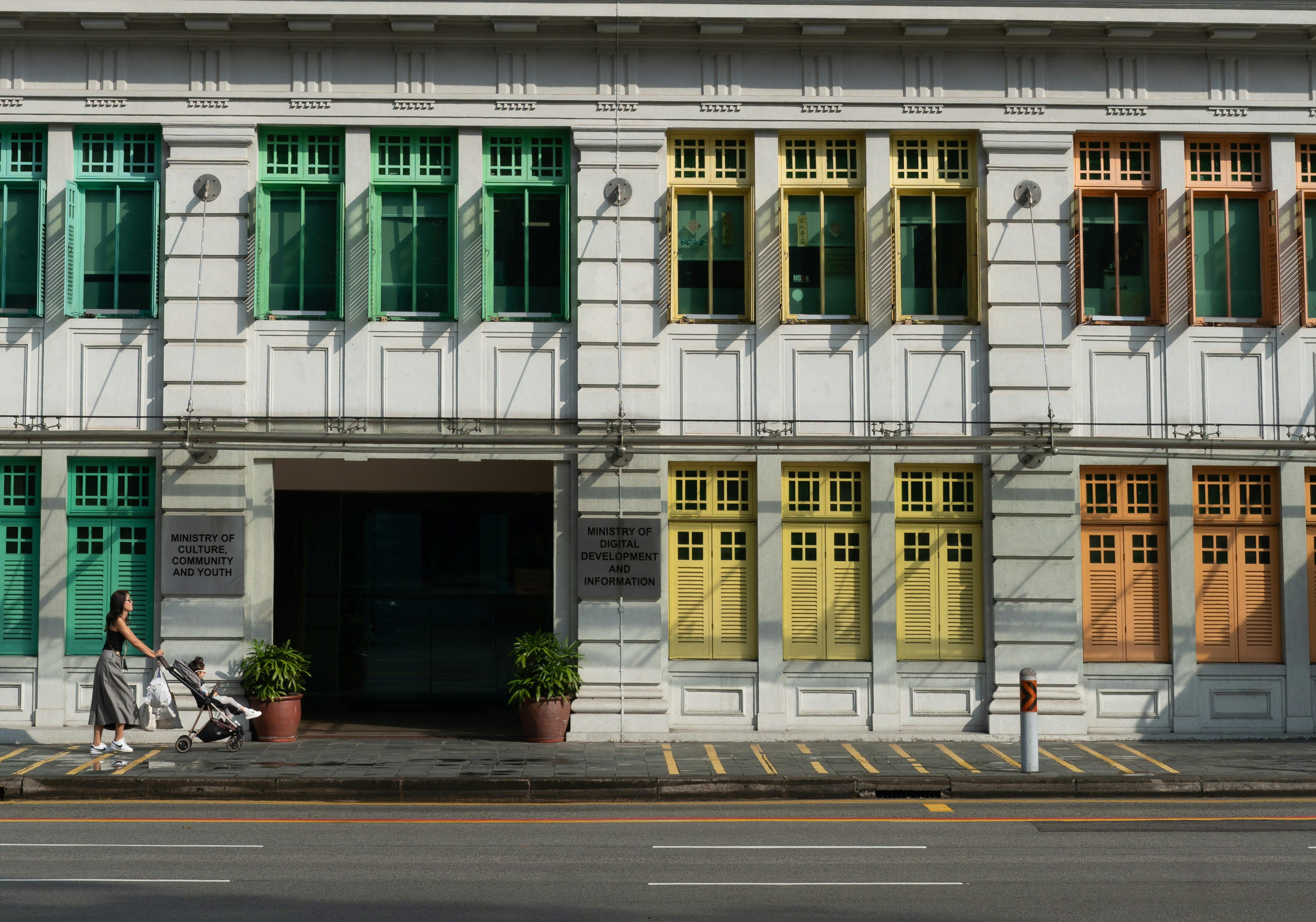 Colorful windows adorn a building, with a person walking.