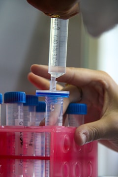 A scientist is using a syringe to filter liquids.