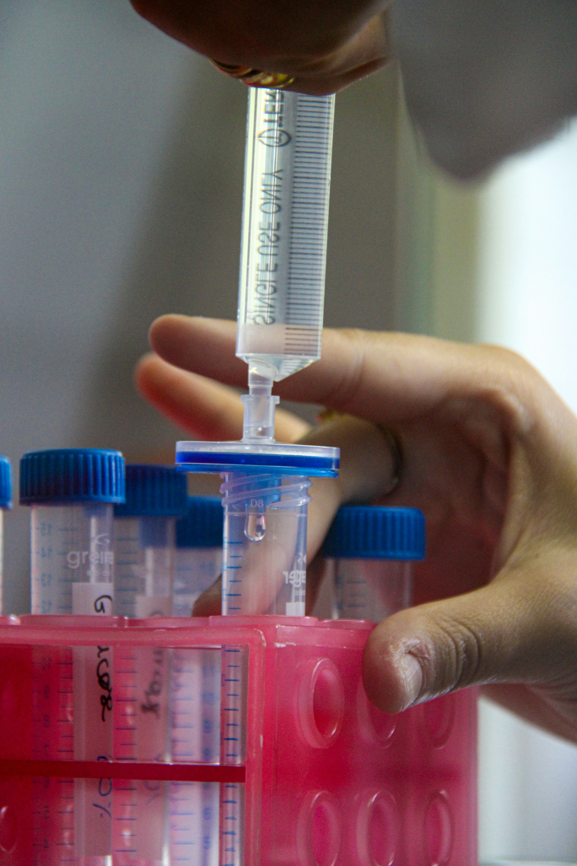 A scientist is using a syringe to filter liquids.