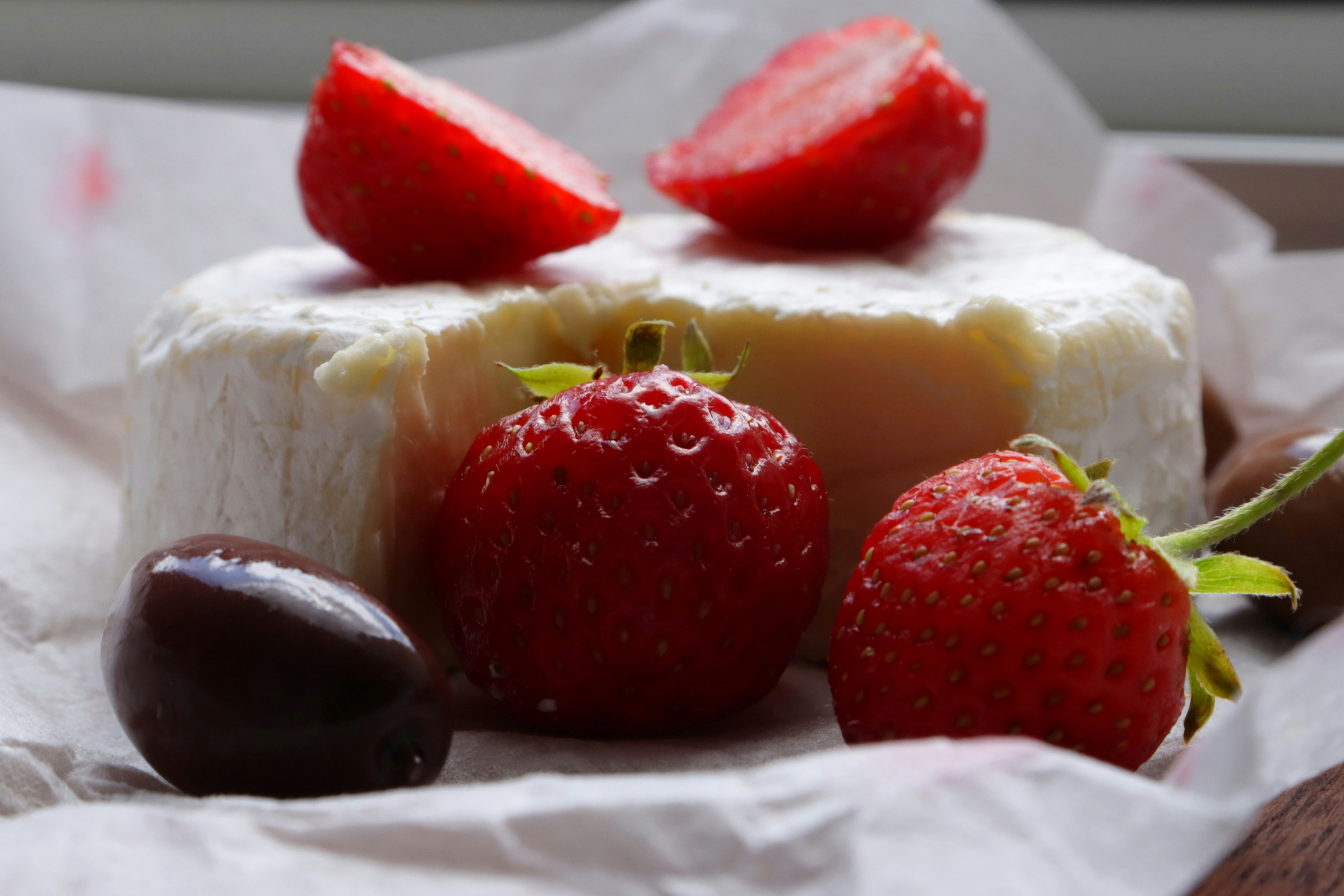 Strawberries, cheese, and a chocolate truffle are shown.