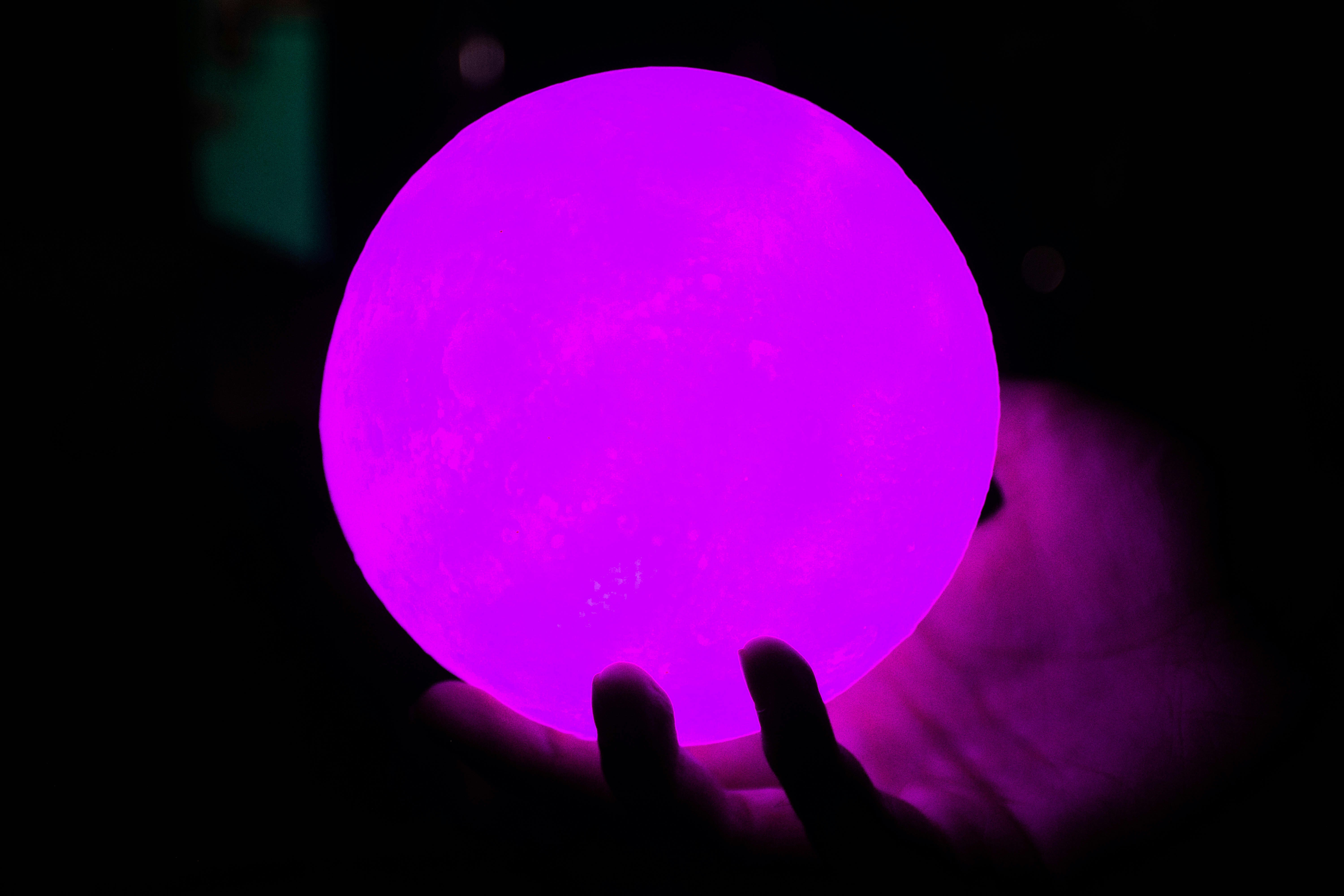 A hand holds a glowing purple orb
