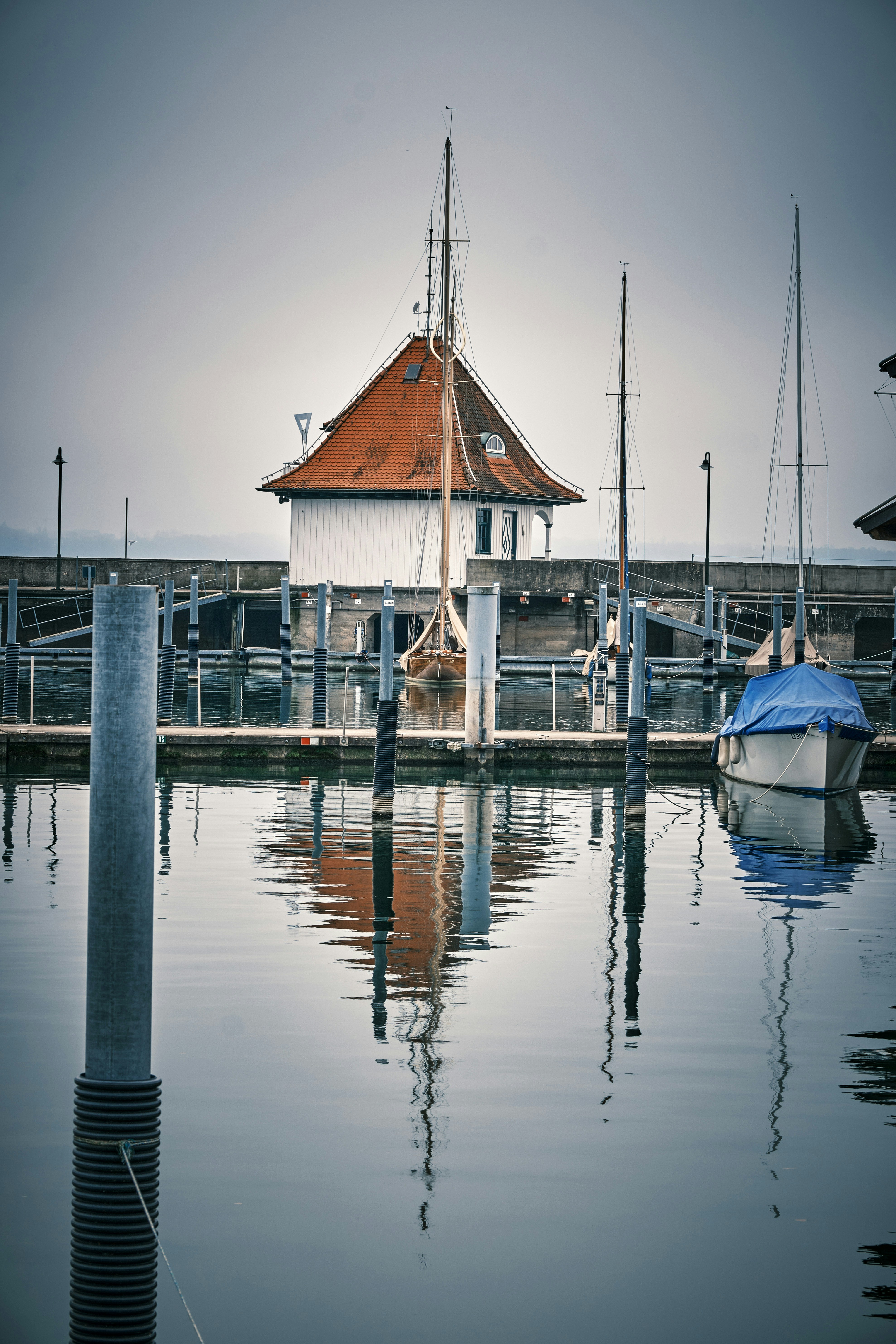 A peaceful harbor with boats reflects in the water.
