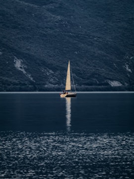 A sailboat glides across the still water.