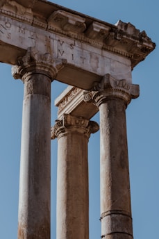 Ancient roman columns stand proudly against the blue sky.