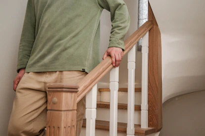 A person walks downstairs, holding the handrail