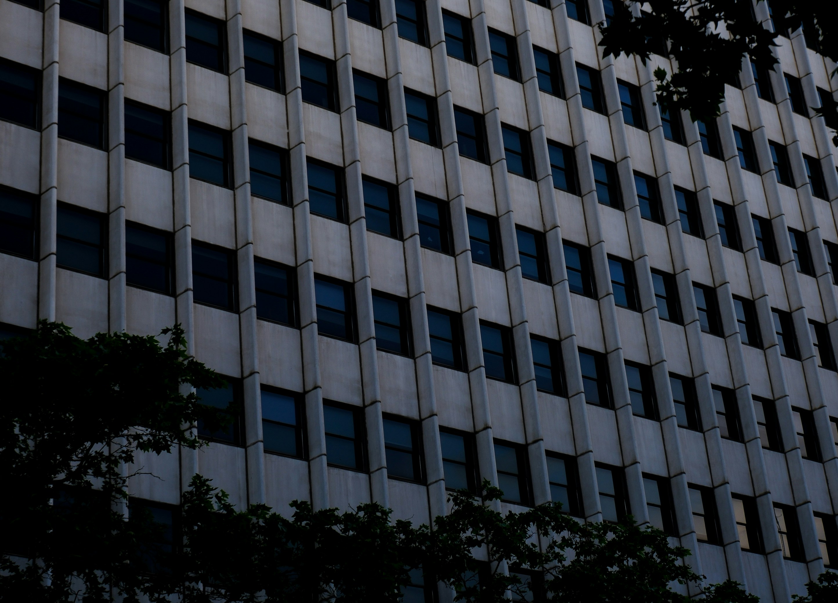 A tall, grey building with numerous windows.