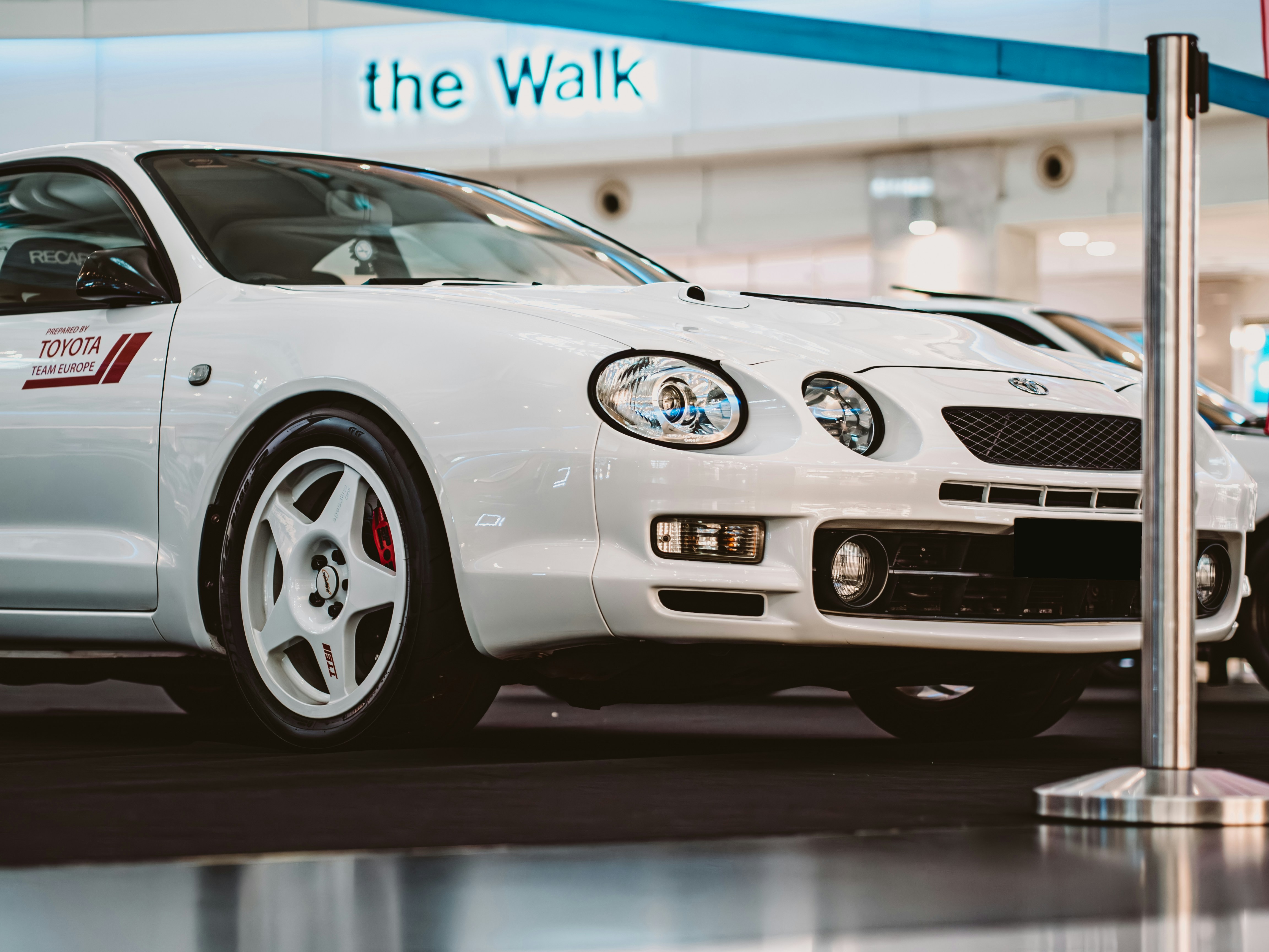 A white sports car is parked indoors.