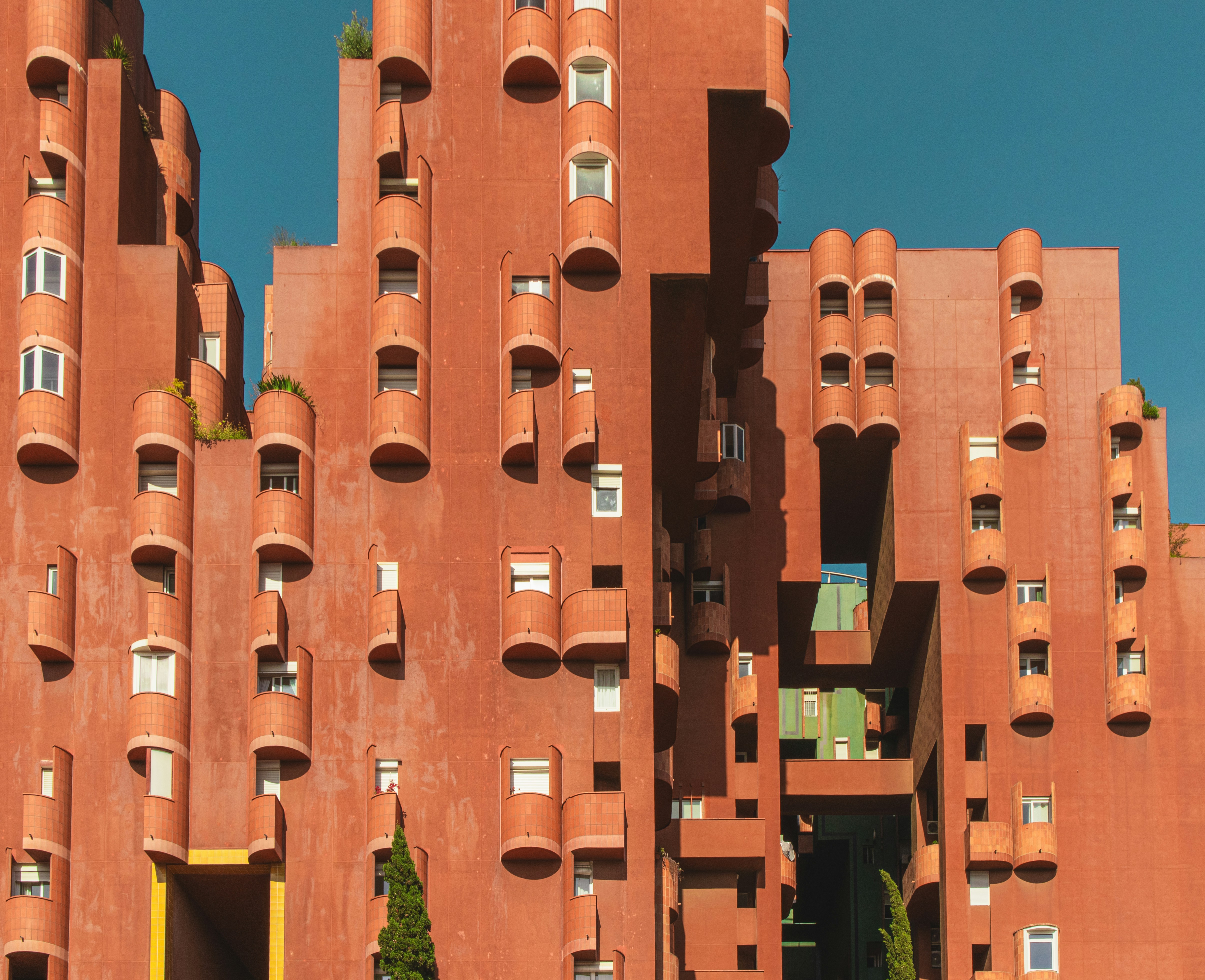 Red terracotta building with unique cylindrical balconies.
