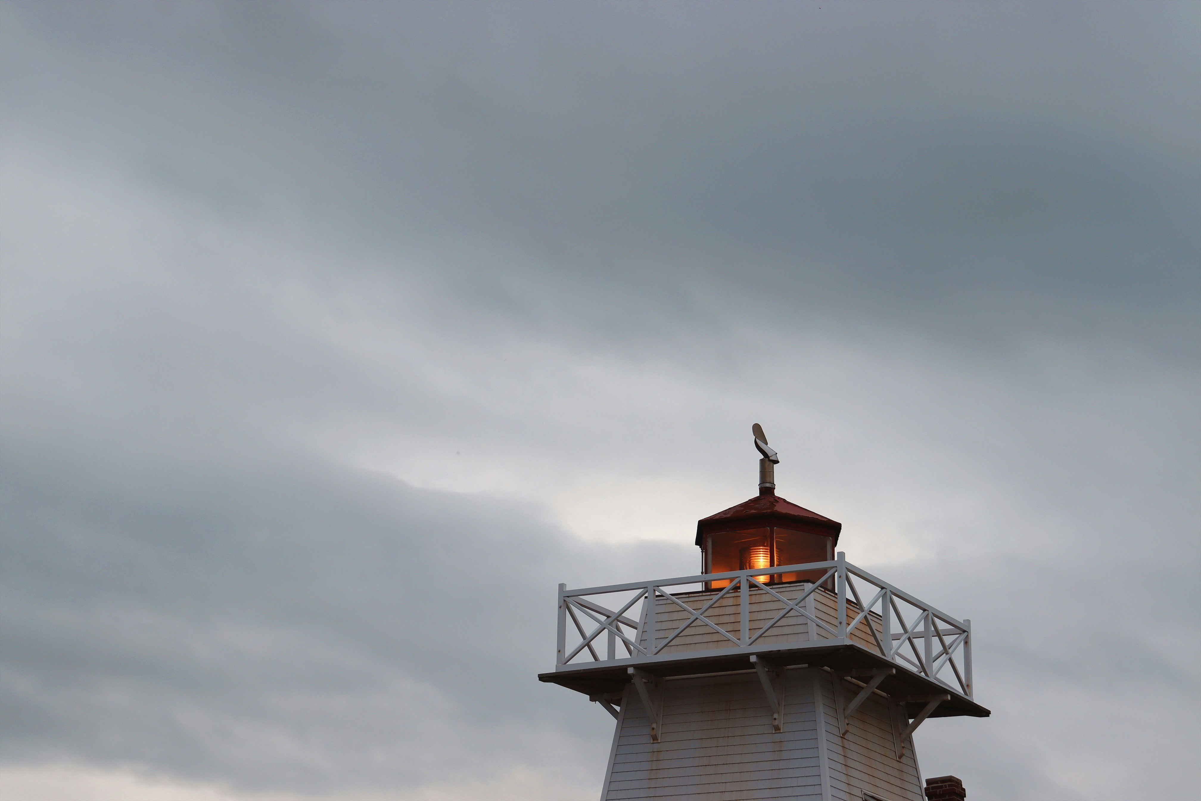 A lighthouse glows against a cloudy sky.