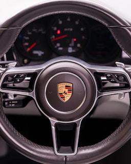 A close-up of a porsche steering wheel.