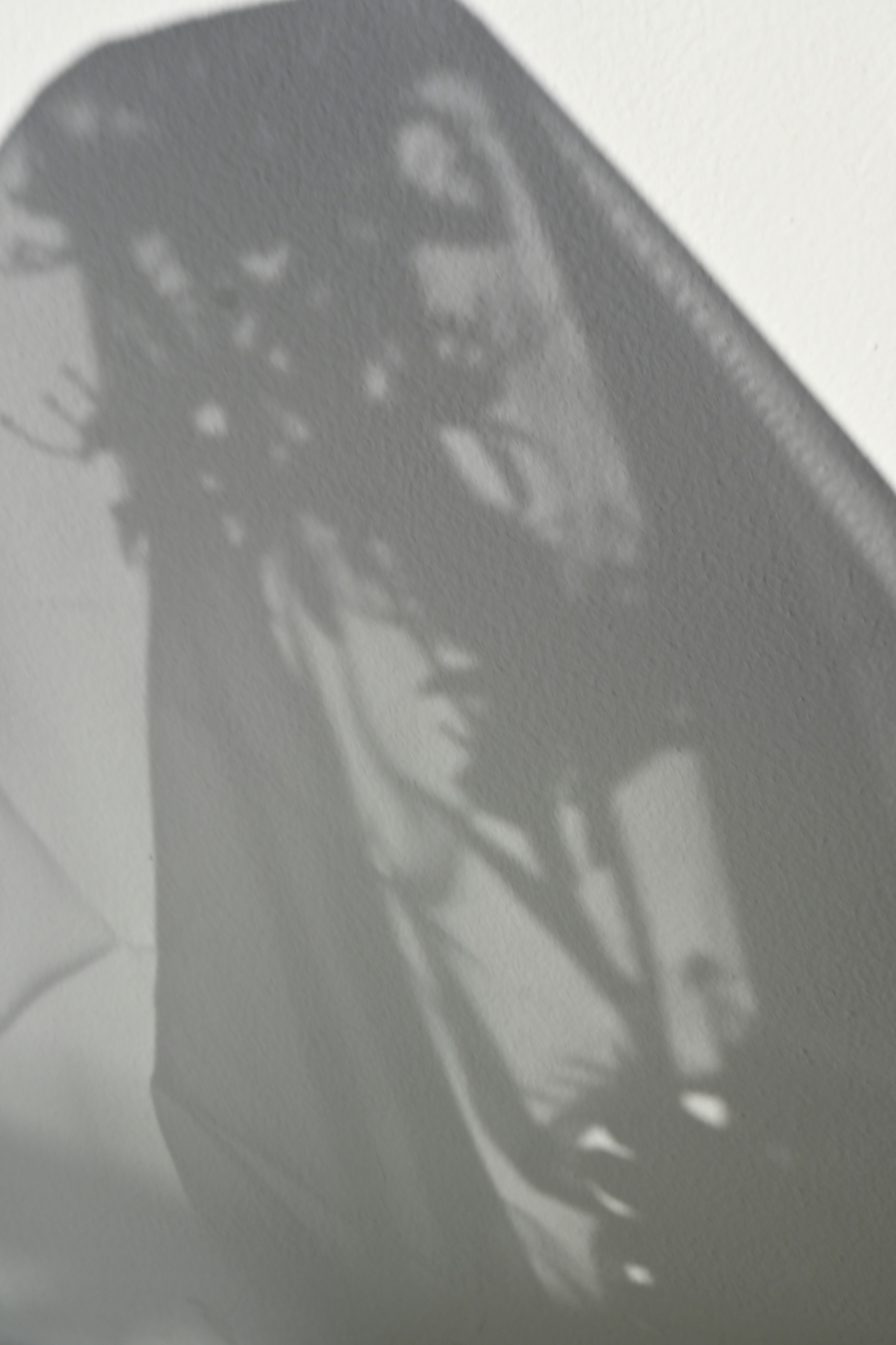 Shadows of fabric and objects are cast on the wall.