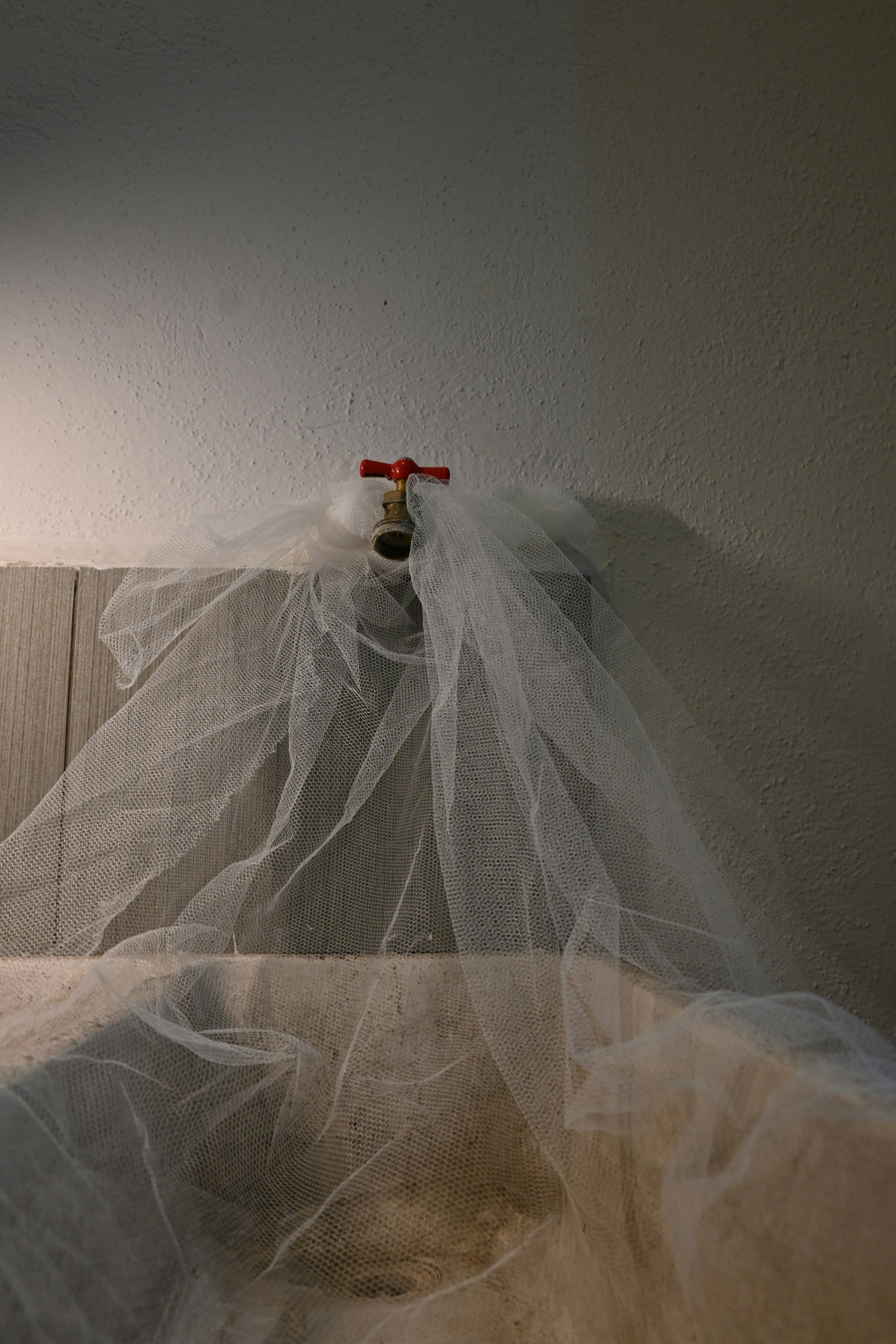 A faucet is draped with a sheer white fabric.