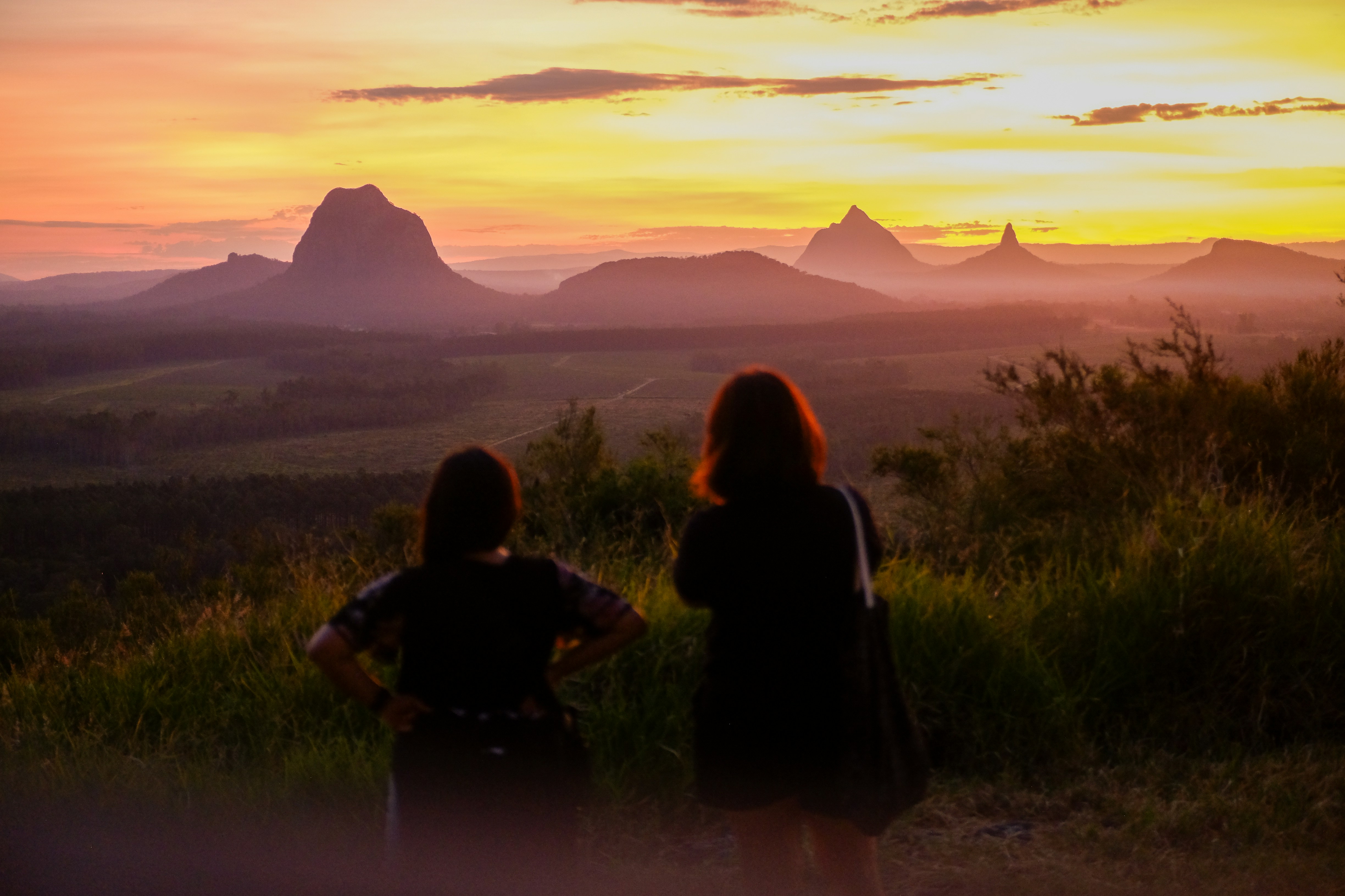 Zwei Personen genießen einen malerischen Sonnenuntergang über den Bergen.