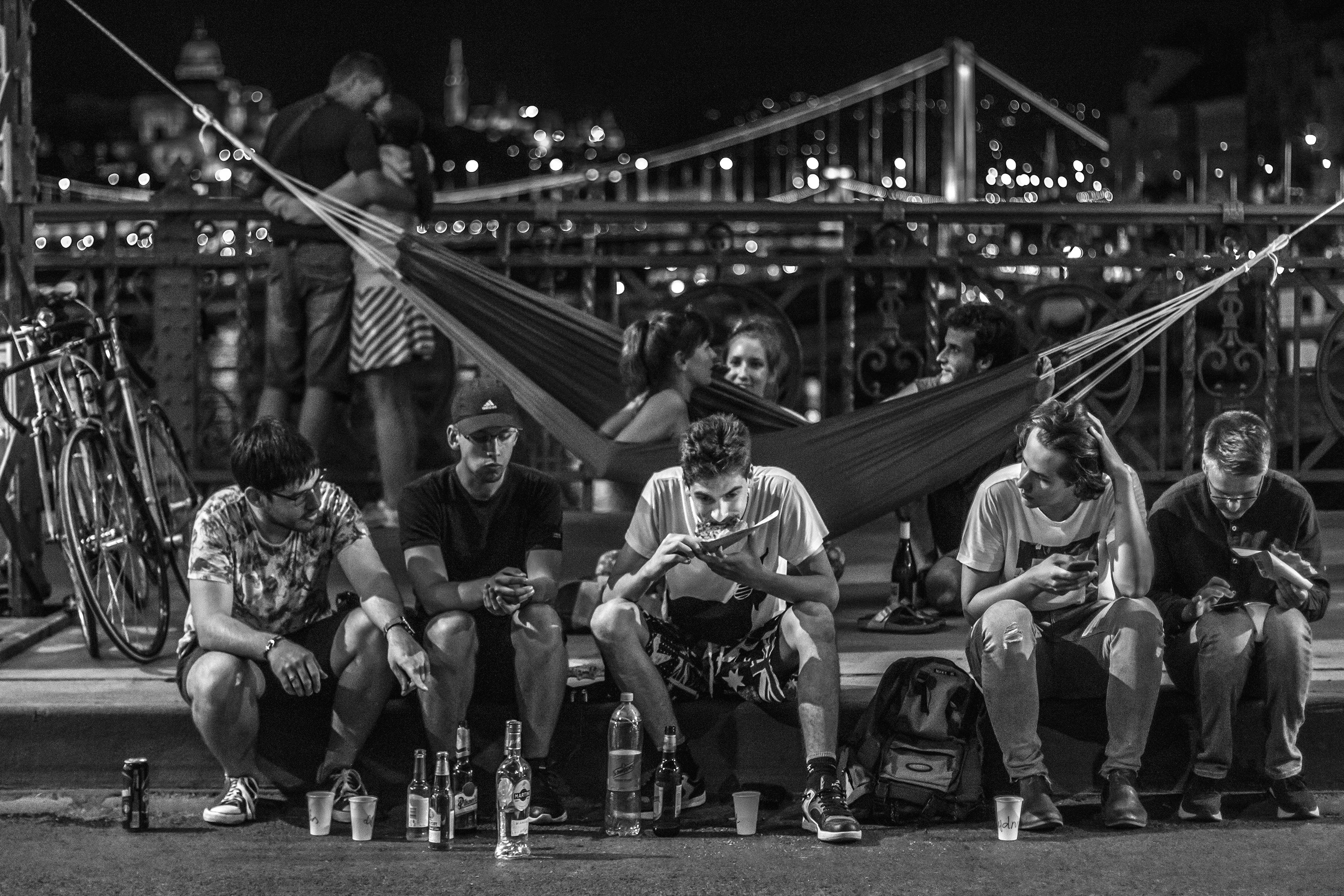 Young people relax with drinks and hammocks at night.