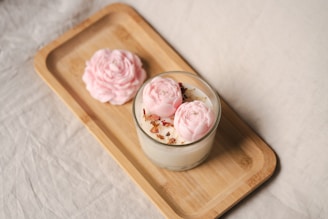 A candle with flowers on a wooden tray.