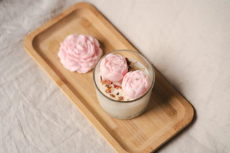 A candle with flowers on a wooden tray.