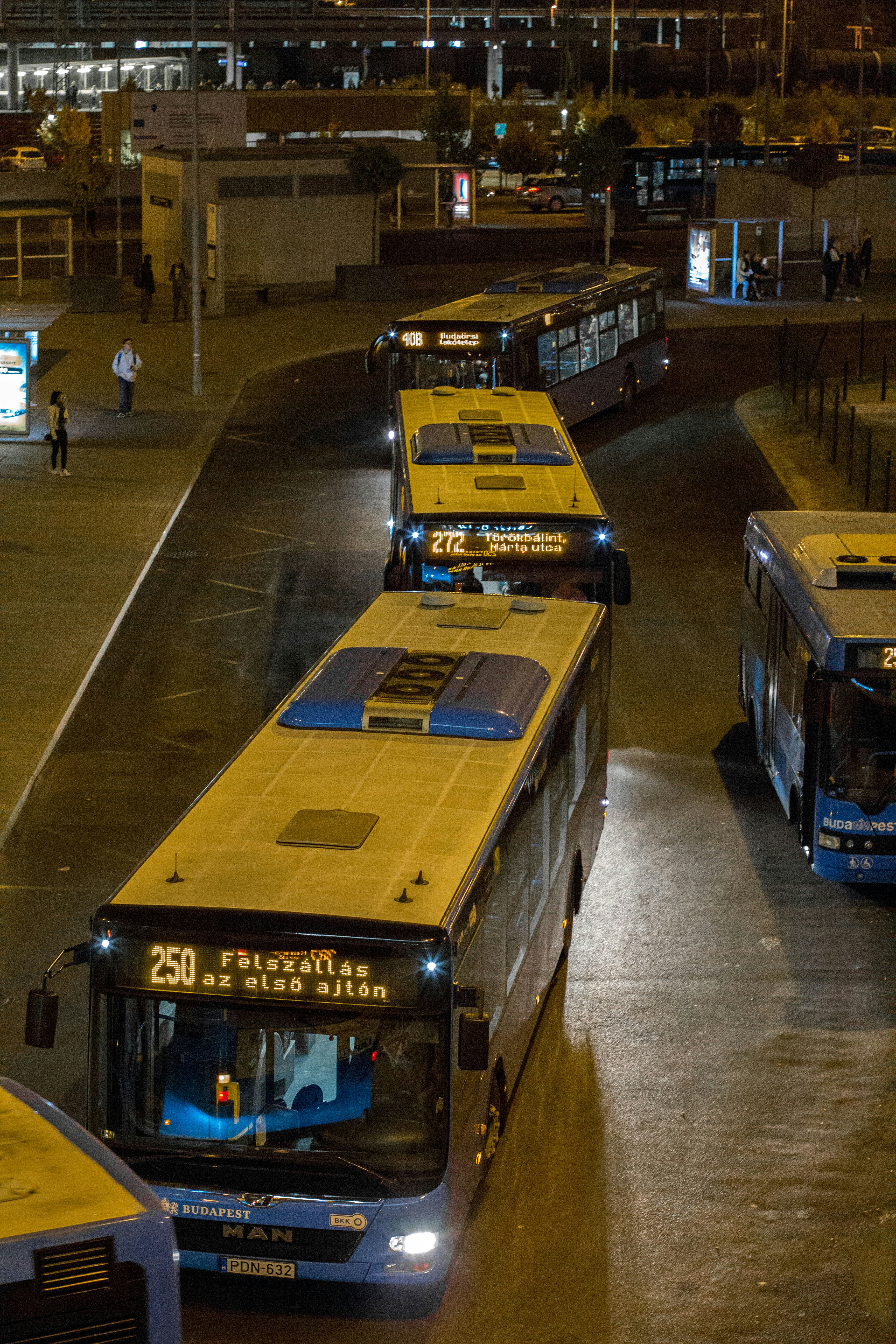 Buses are lined up at a bus station at night.