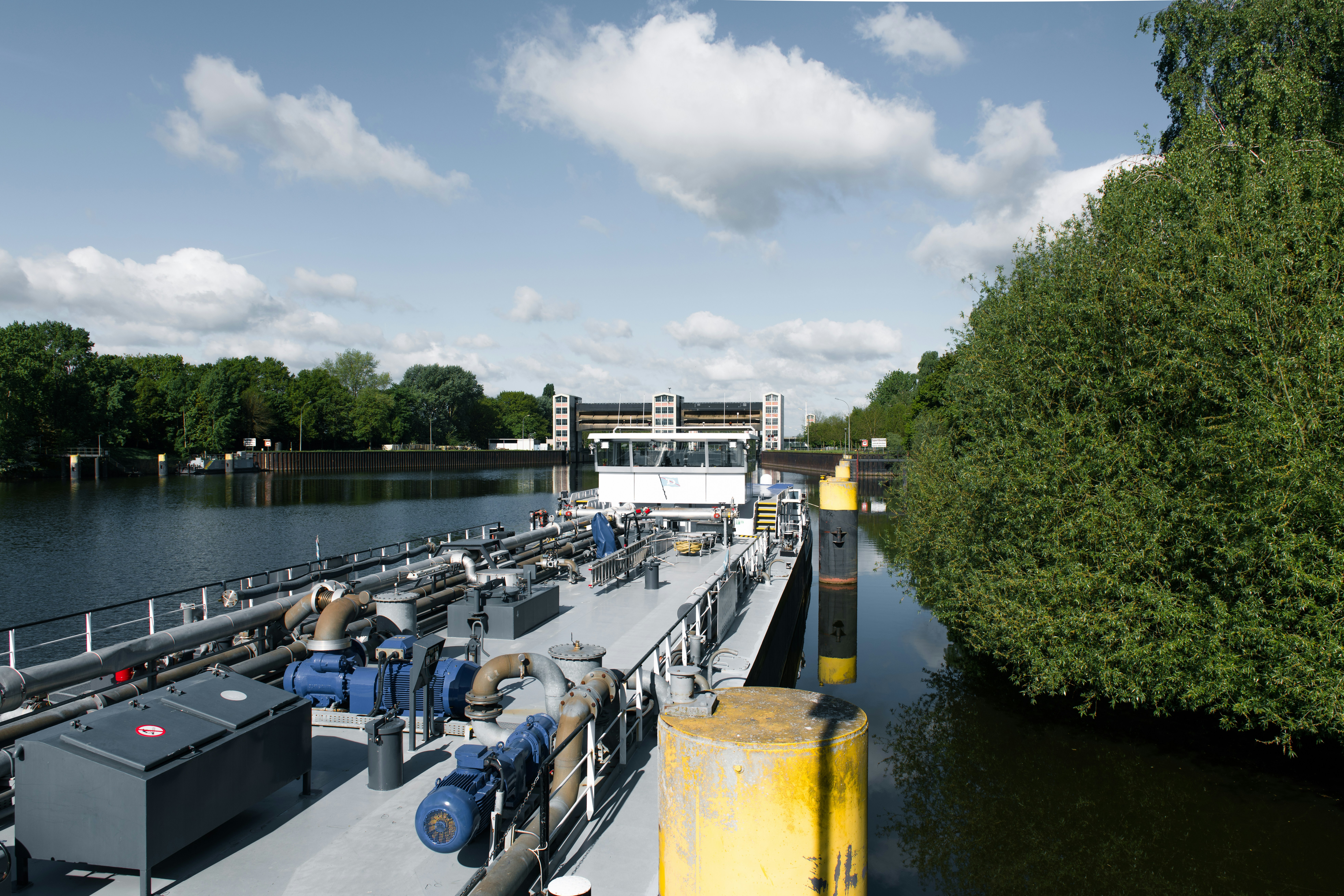 A barge sails through a waterway with dense greenery.