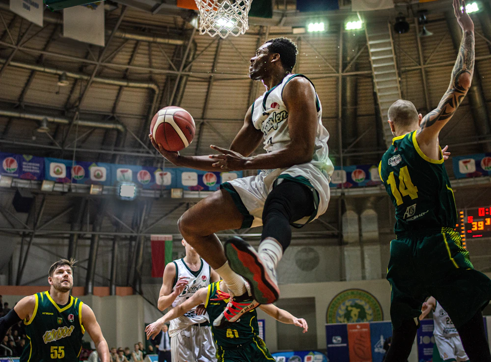 Basketball player rising toward the hoop as defenders contest a dunk
