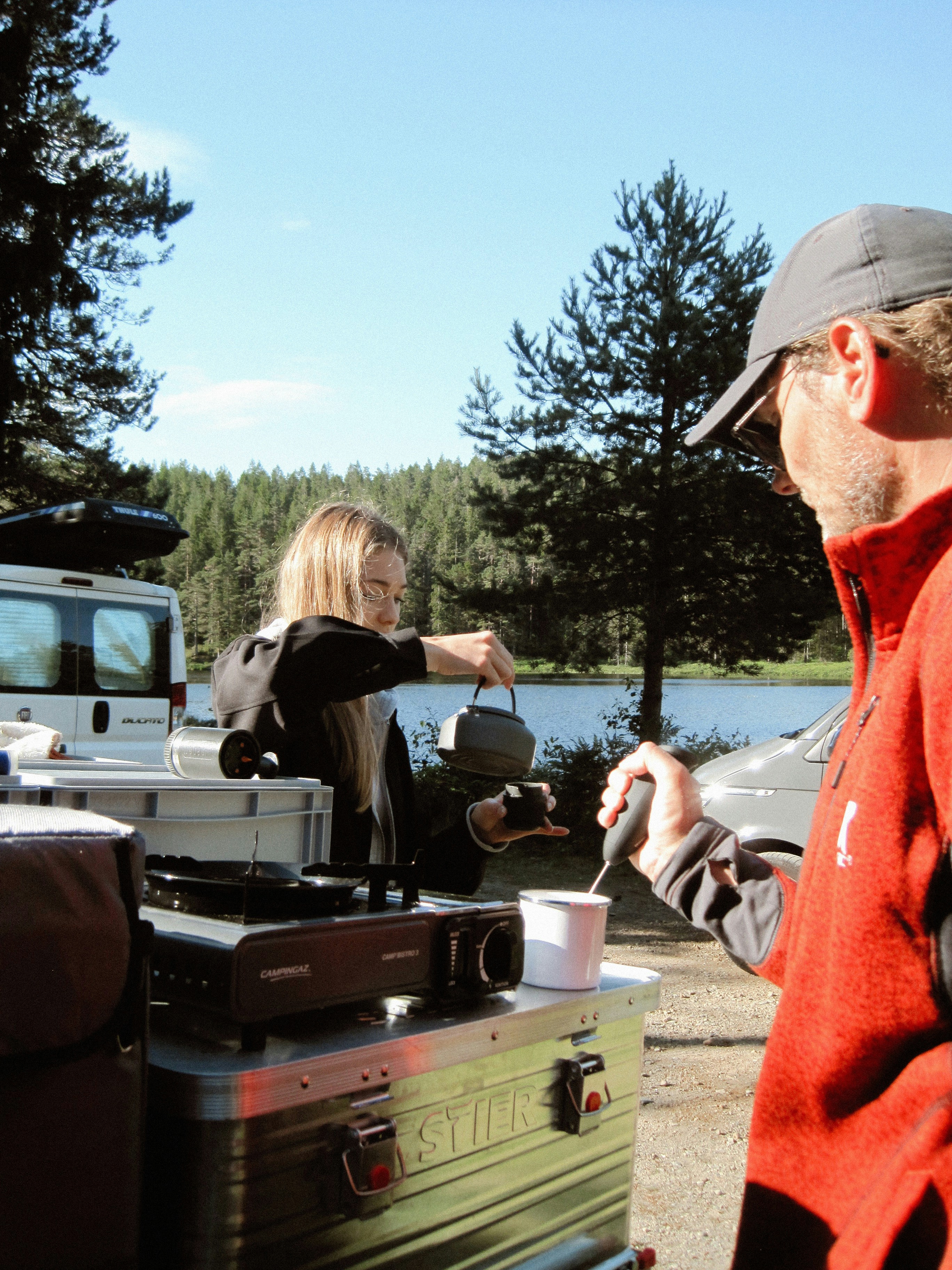 Le persone si godono il tè mentre sono in campeggio vicino a un lago.