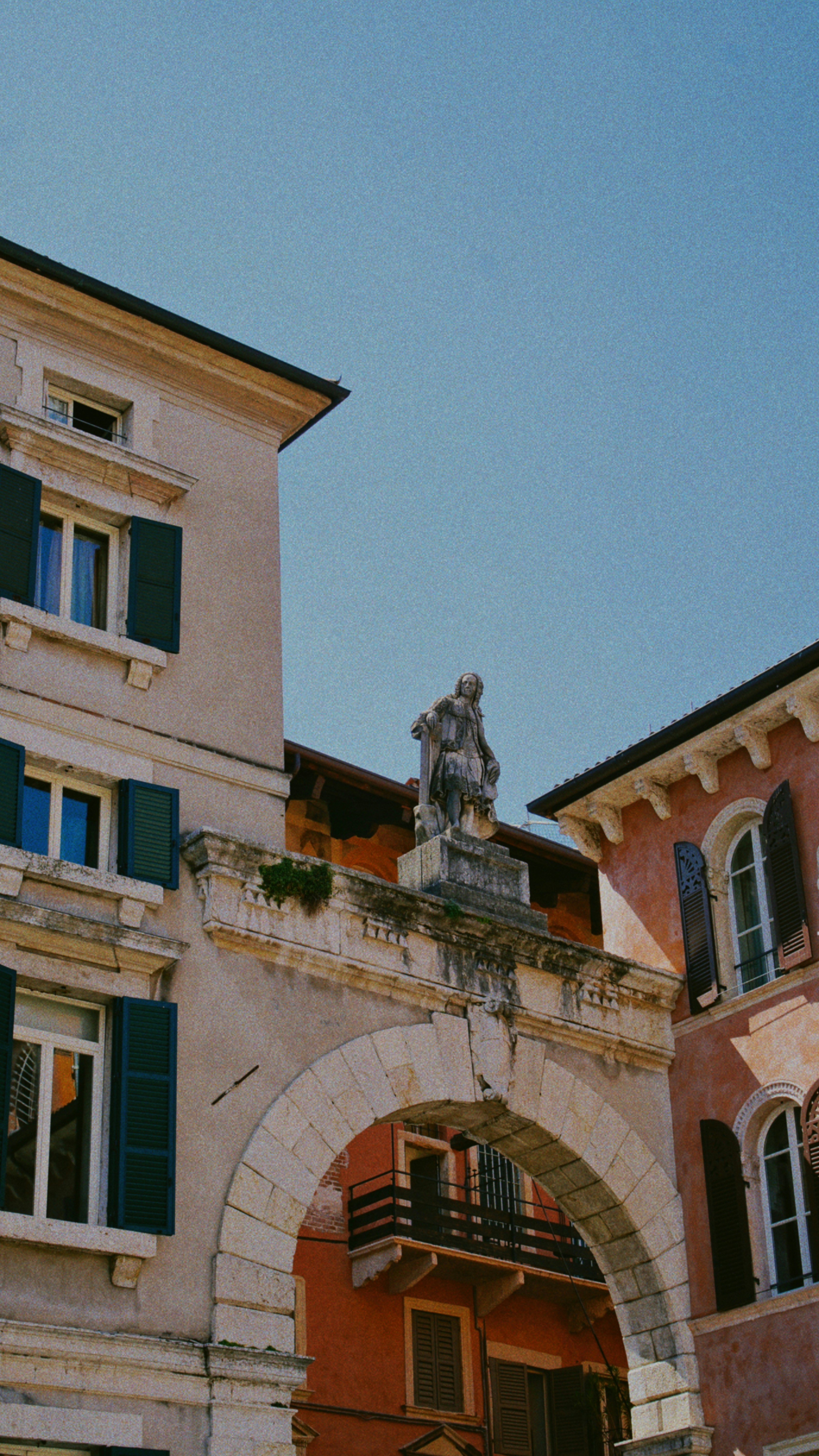 An arched doorway leads to italian buildings.